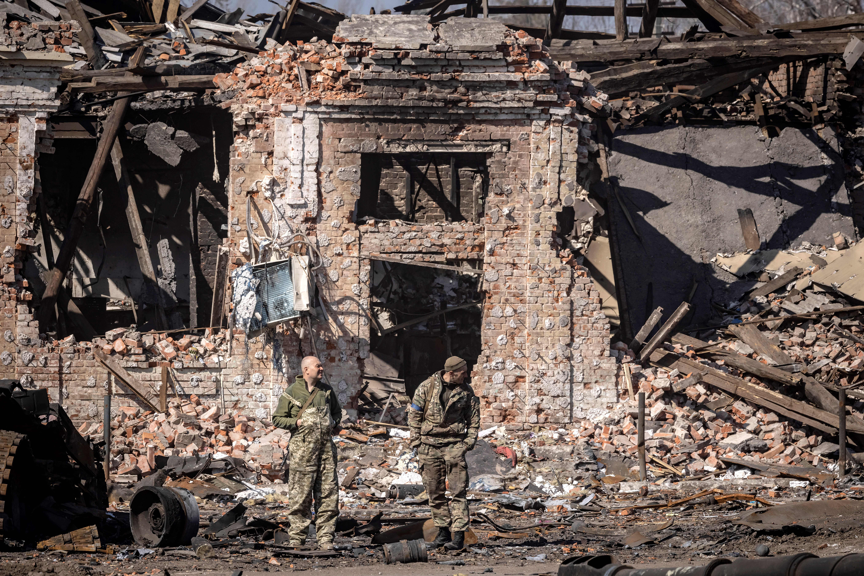 March 29: Ukrainian servicemen stand next to the rubble of a destroyed building in the northeastern Ukrainian city of Trostyanets.