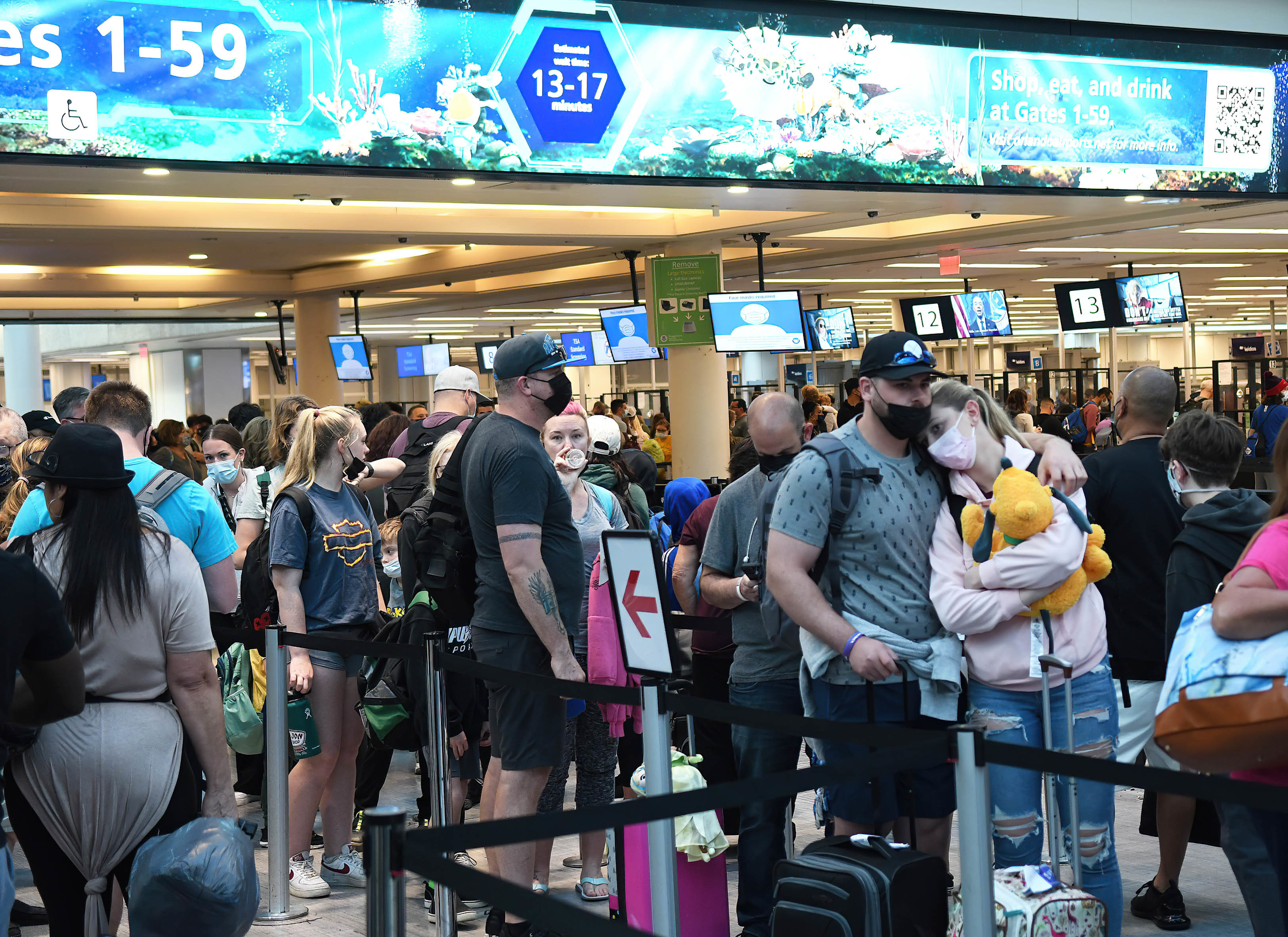 Spring break passengers wait in a TSA security line at Orlando International Airport. While COVID-19 face masks are still required, crowds have increased over last year. (SOPA Images/LightRocket via Getty Images)