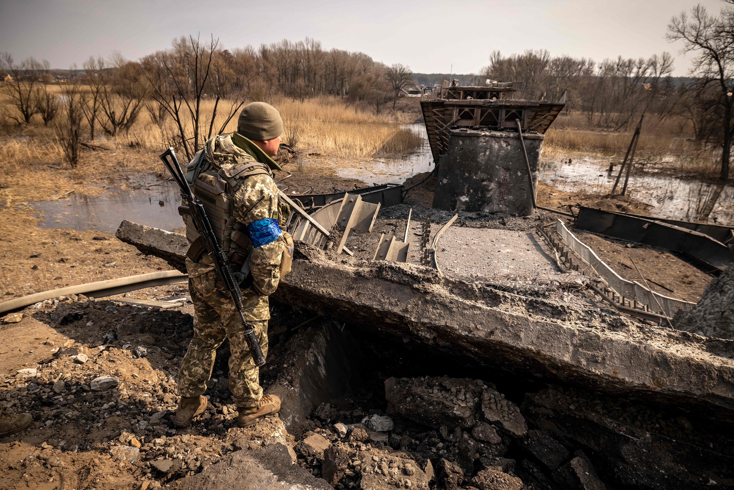 March 30: A Ukrainian soldier patrols near a bridge destroyed by the Russian army in the town of Rogan, east of Kharkiv.