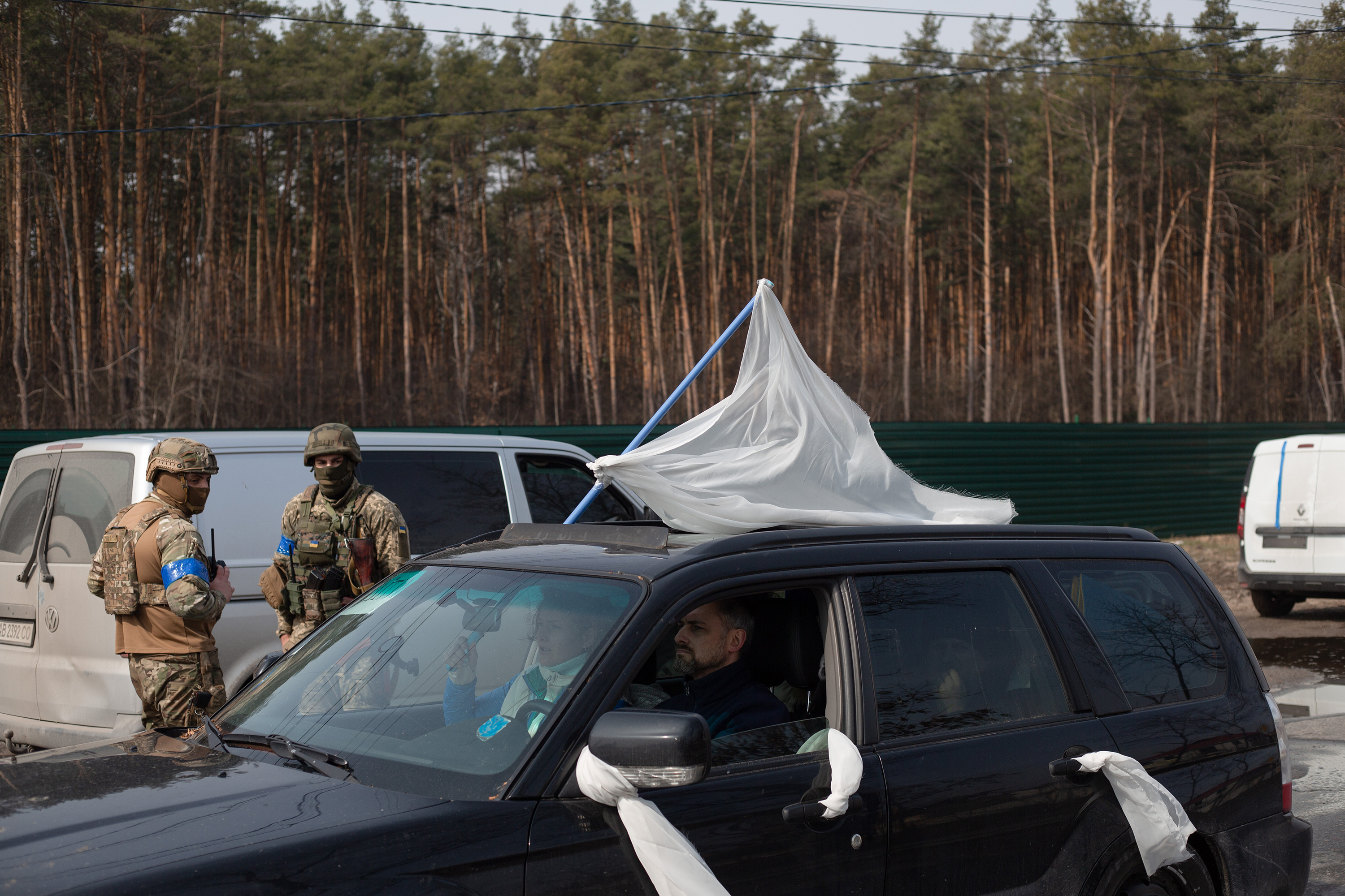 March 31: An evacuation car with civilians passes by Ukrainian servicemen in Stoyanka, Ukraine.