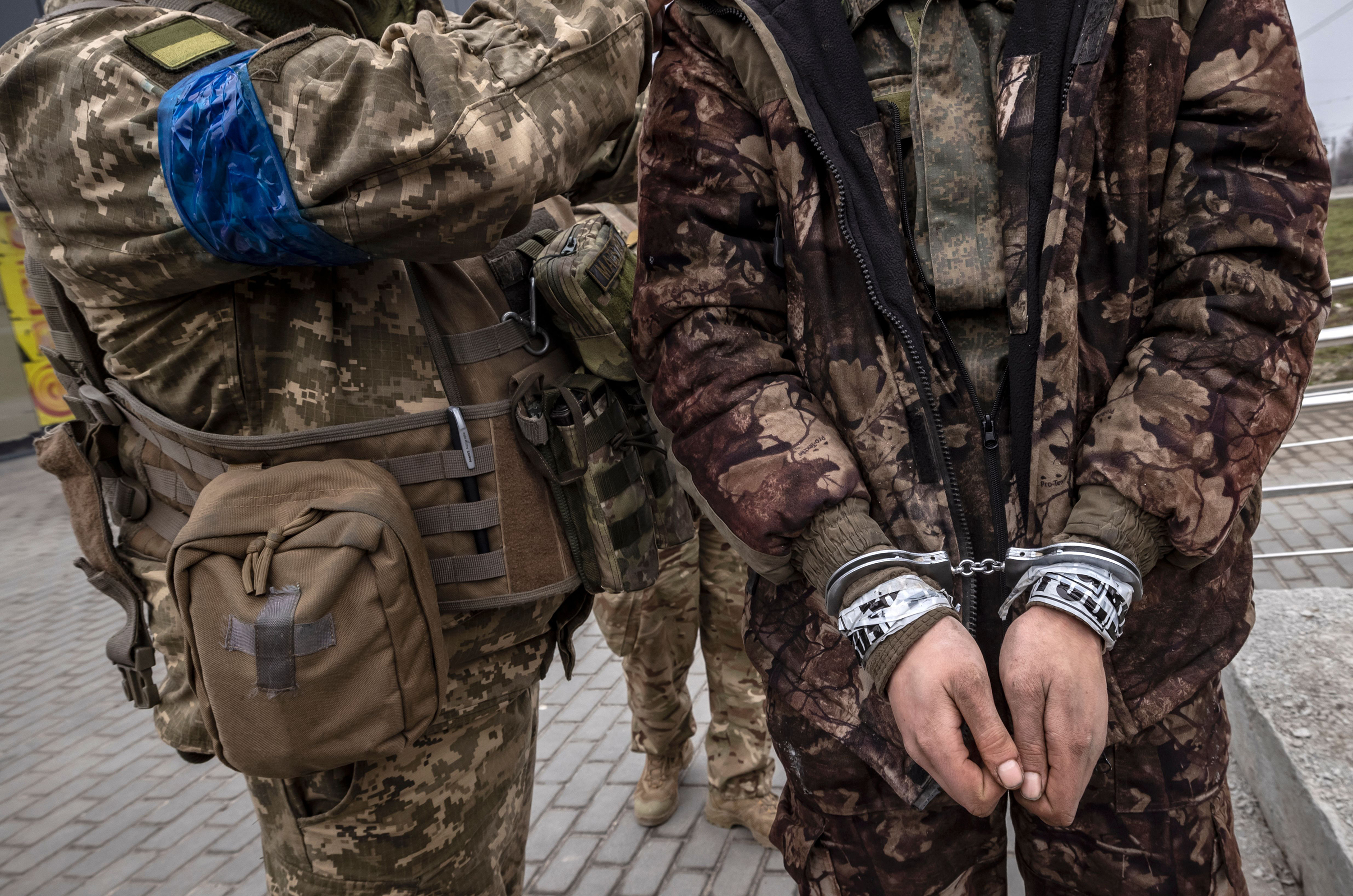 March 31: A Ukrainian serviceman stands past a handcuffed Russian soldier in Kharkiv.