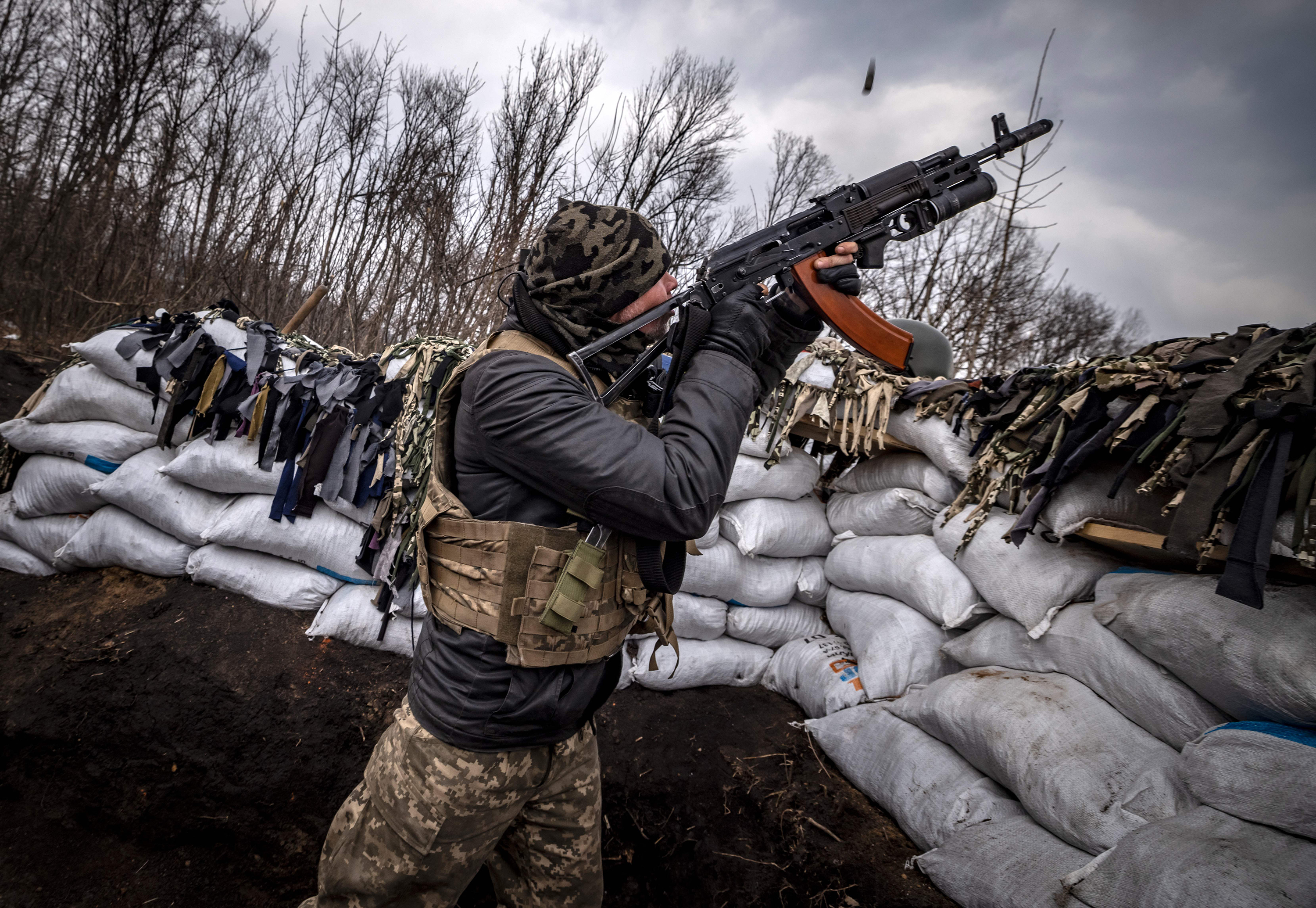 March 31: A Ukrainian serviceman shoots at a Russian drone with an assault rifle from a trench at the front line east of Kharkiv.