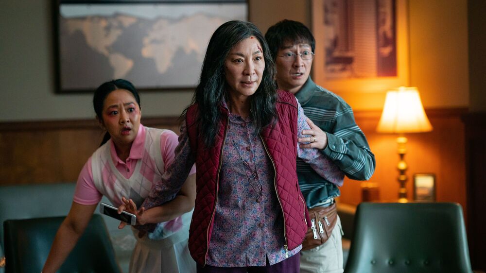 Michelle Yeoh (center) plays Evelyn Wang, a Chinese immigrant who owns a failing laundromat. She protects her daughter Joy (left), played by Stephanie Hsu, and her husband Waymond (right), played by Ke Huy Quan. (A24)