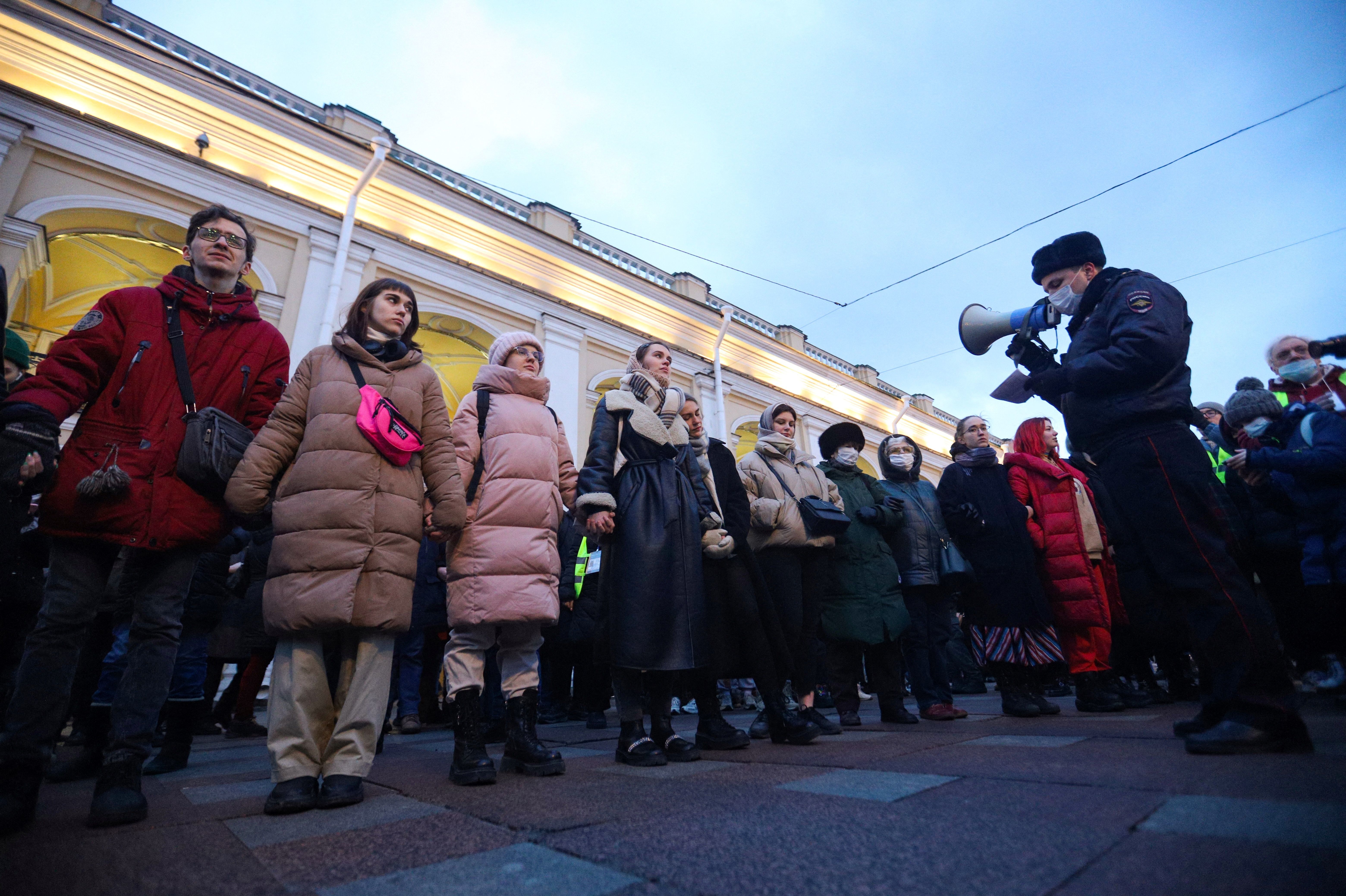A police officer uses a loudspeaker to address people gathered in St. Petersburg to protest Russia's invasion of Ukraine on Feb. 24. (AFP via Getty Images)