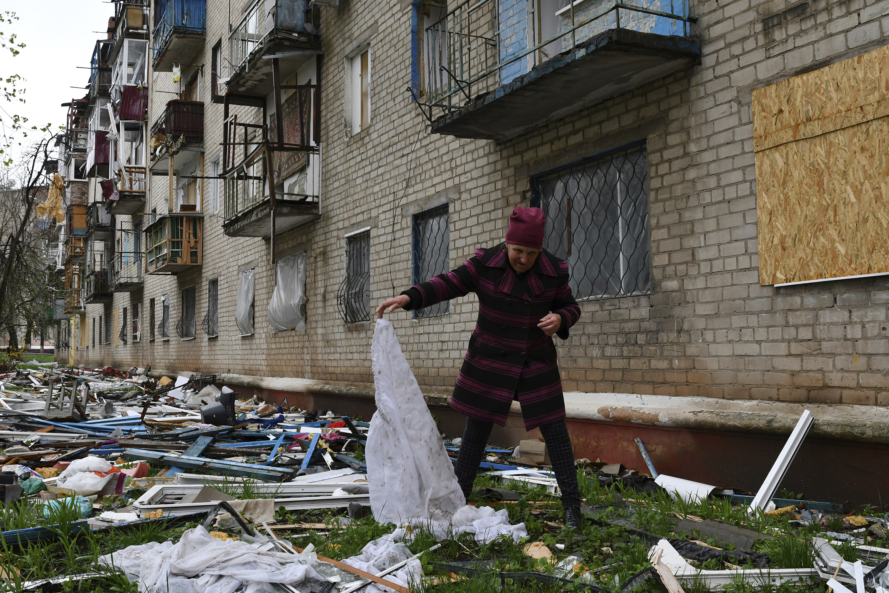 April 14: A woman looks for goods dropped from the apartment building partly damaged by shelling, in Kramatorsk, Ukraine.