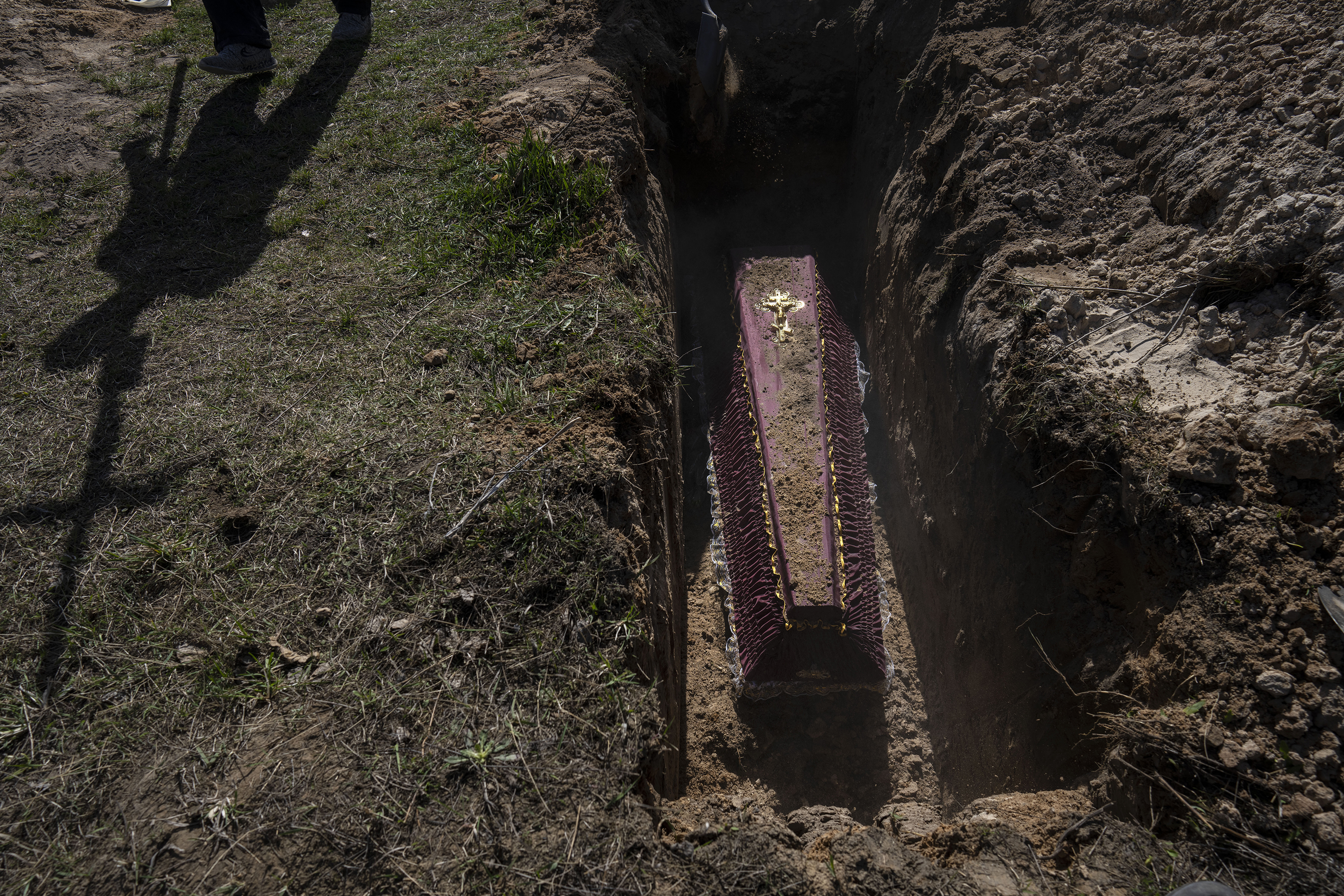 April 14: A cemetery worker carries a cross for the tomb of Tetyana Gramushnyak, 75, who was killed by shelling on March 19 while cooking food outside her home in Bucha, on the outskirts of Kyiv, Ukraine.