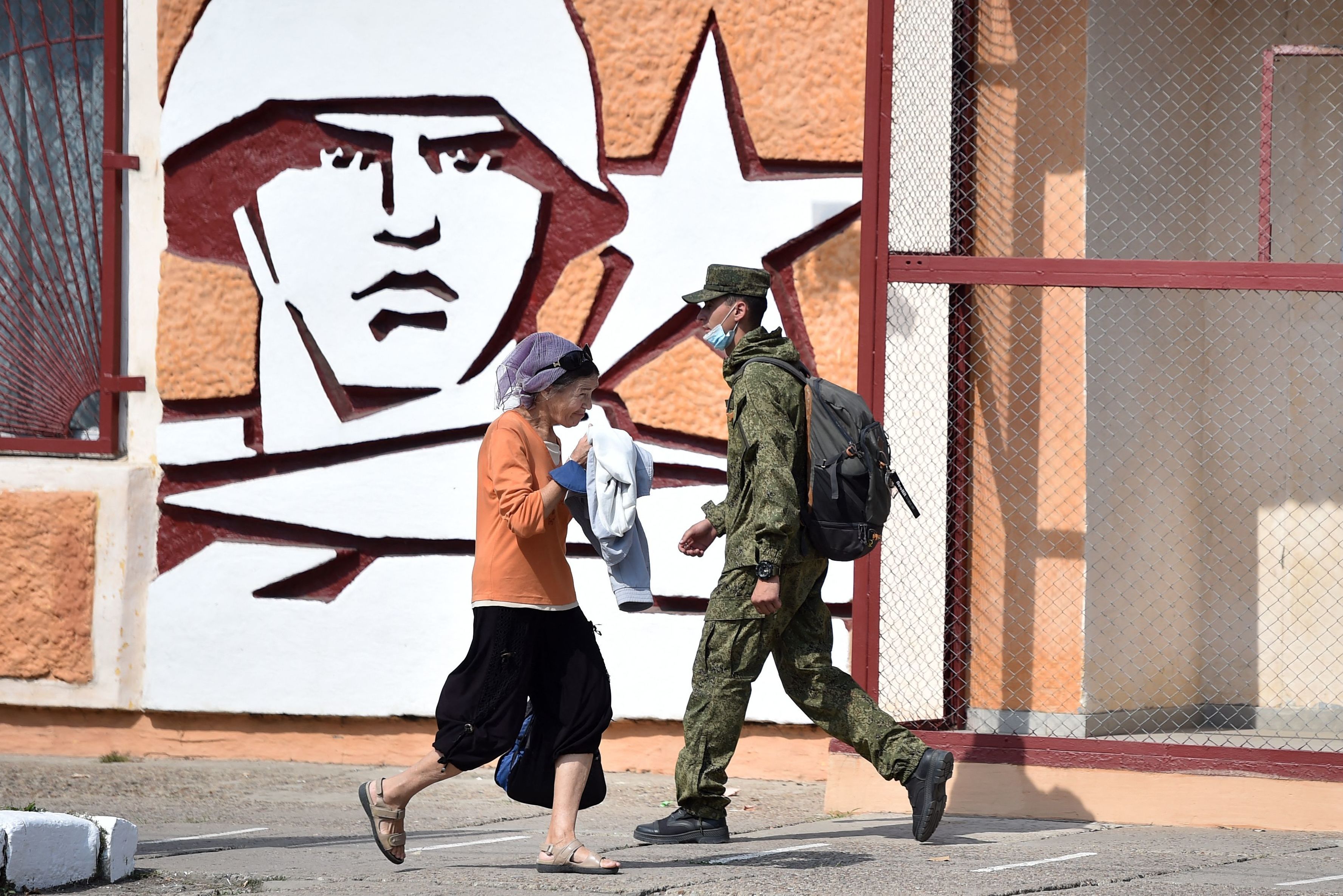 A soldier and a woman walk past the headquarters for Russian troops in September 2021 in the town of Tiraspol, in Trans-Dniester, a pro-Russian region that declared independence from Moldova but is internationally unrecognized. Russia has stationed 1,500 soldiers in the area. (AFP via Getty Images)