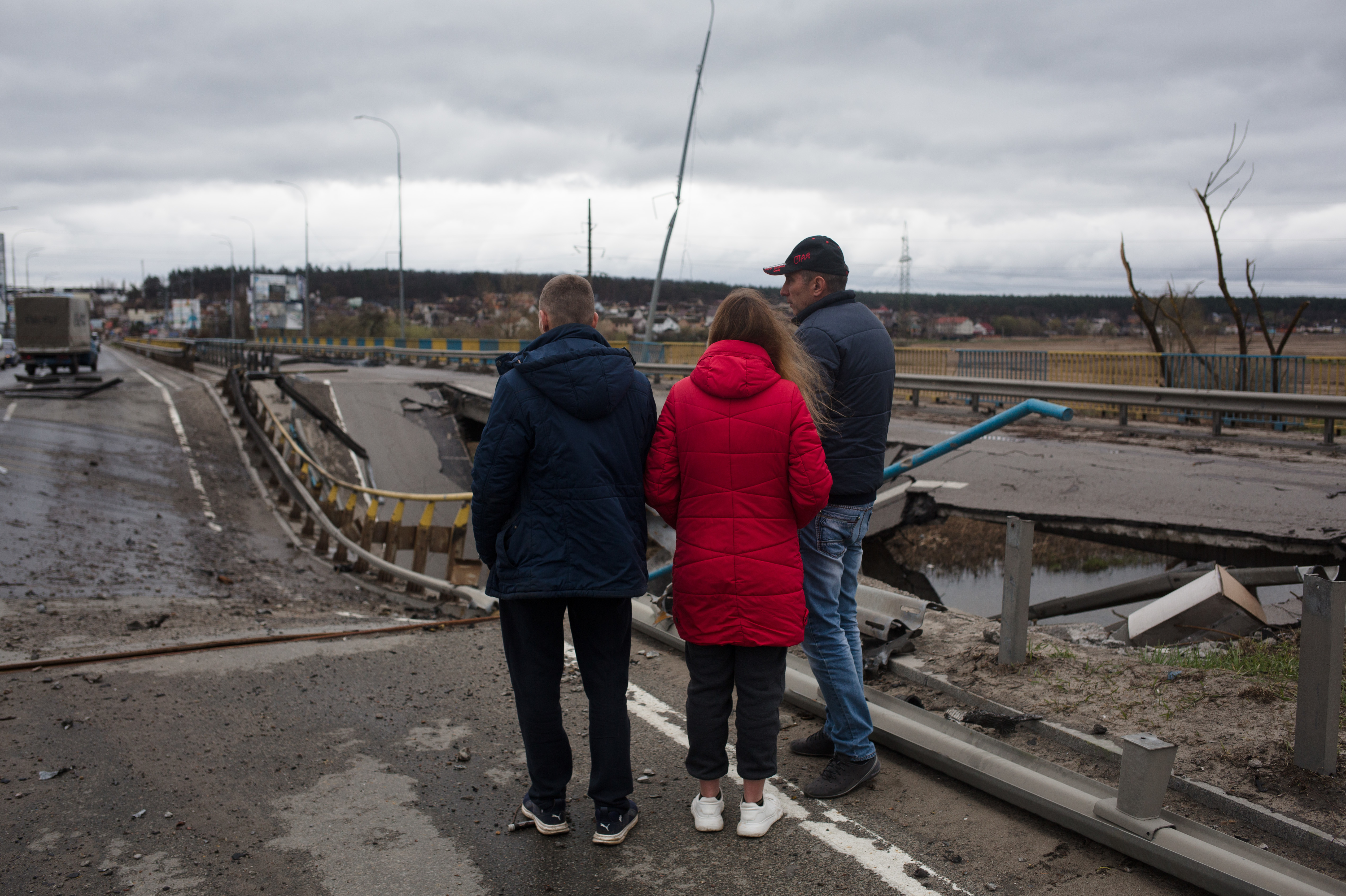 Residents of Irpin, Ukraine, near Kyiv stand on a damaged bridge on Saturday. Kyiv's mayor is urging people to remain vigilant after more strikes occurred overnight in the area. (Getty Images)