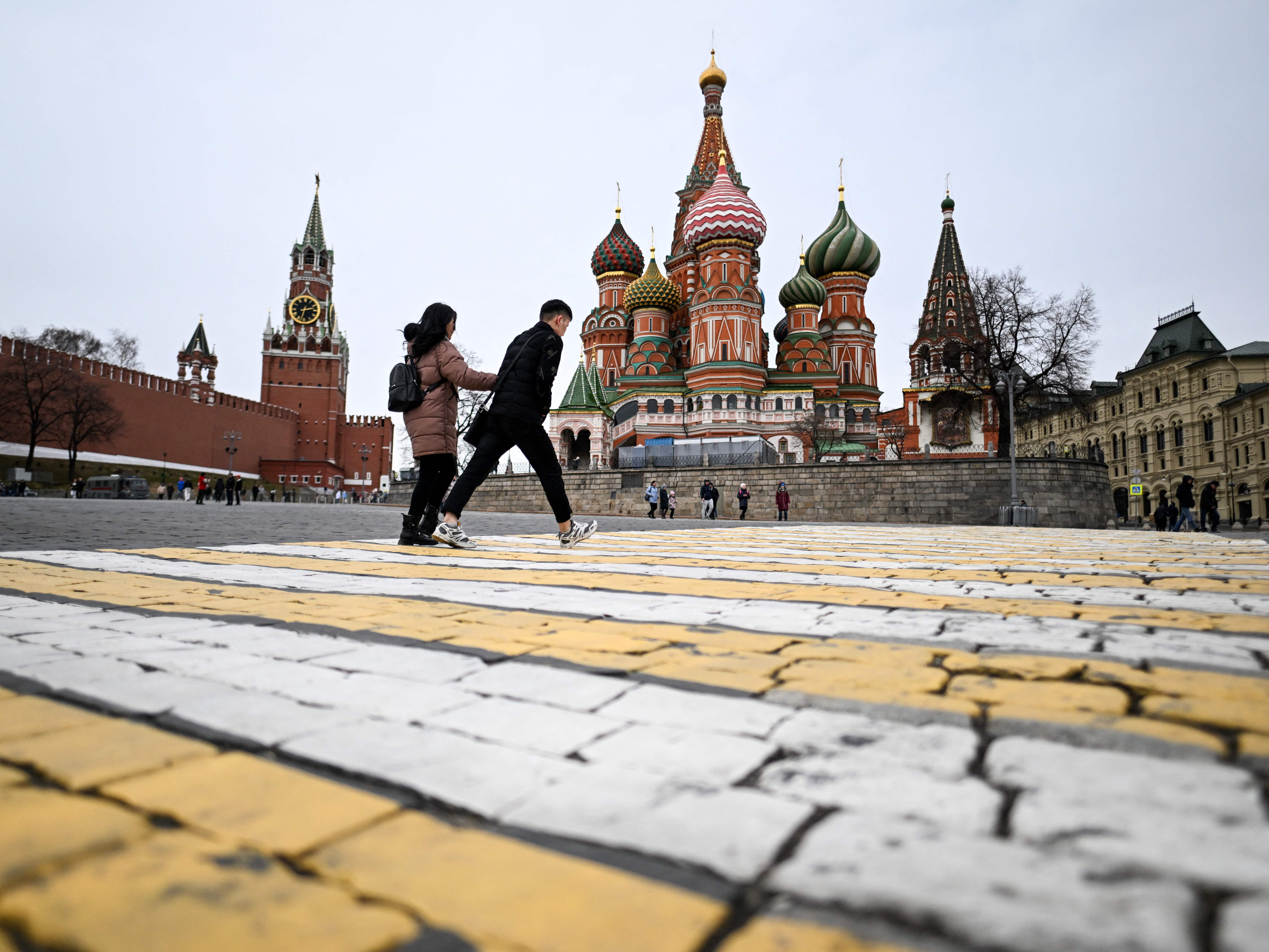 A couple walk in front of the Kremlin's Spasskaya Tower and St Basil's cathedral in downtown Moscow. While 80% of poll respondents say they support Russia's military, some have mixed feelings. (AFP via Getty Images)