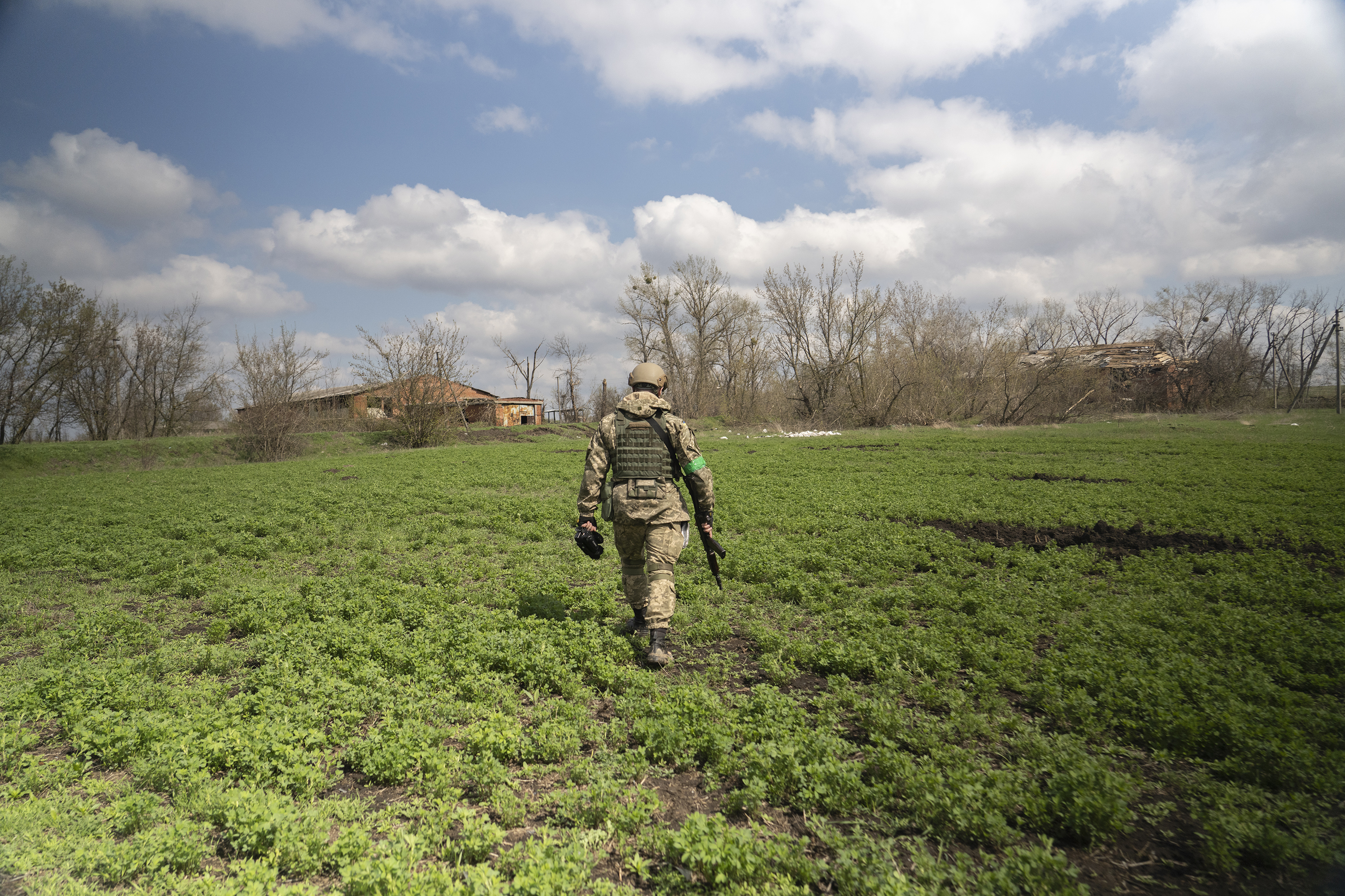Capt. Daniil, a public affairs officer in the Ukrainian military, walks through a field in Mala Rohan, on the outskirts of Ukraine's northeastern city of Kharkiv. He is recording the aftermath of fighting between occupying Russian soldiers and Ukrainian forces. (NPR)