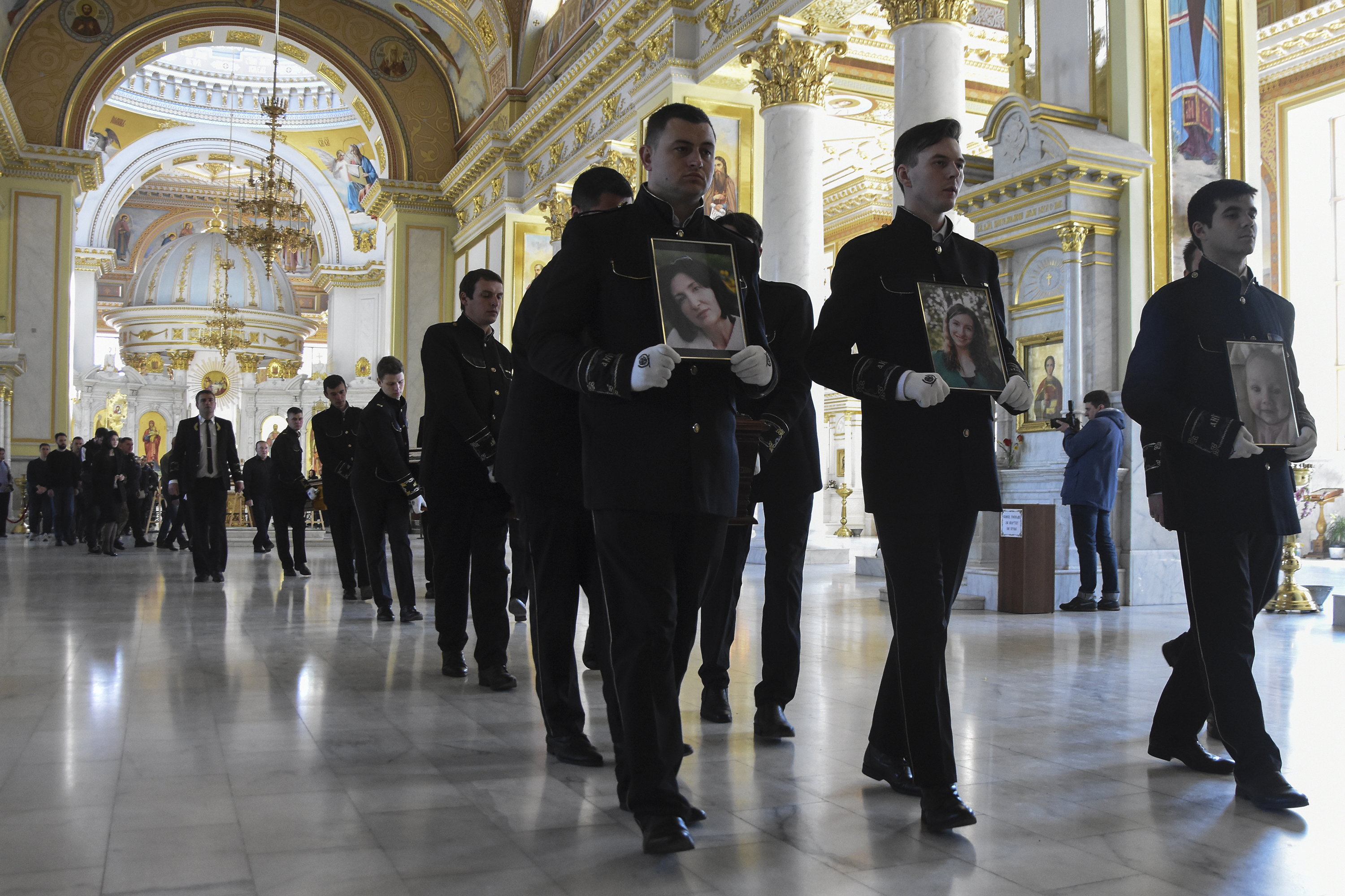 April 27: Men carry portraits of, from right, Valerya Glodan, 28, and her mother, Lyudmila Yavkina, 54, who were killed in their apartment by shelling with 3-month-old infant Kira Glodan, during a funeral ceremony at the Transfiguration Cathedral in Odessa, Ukraine.