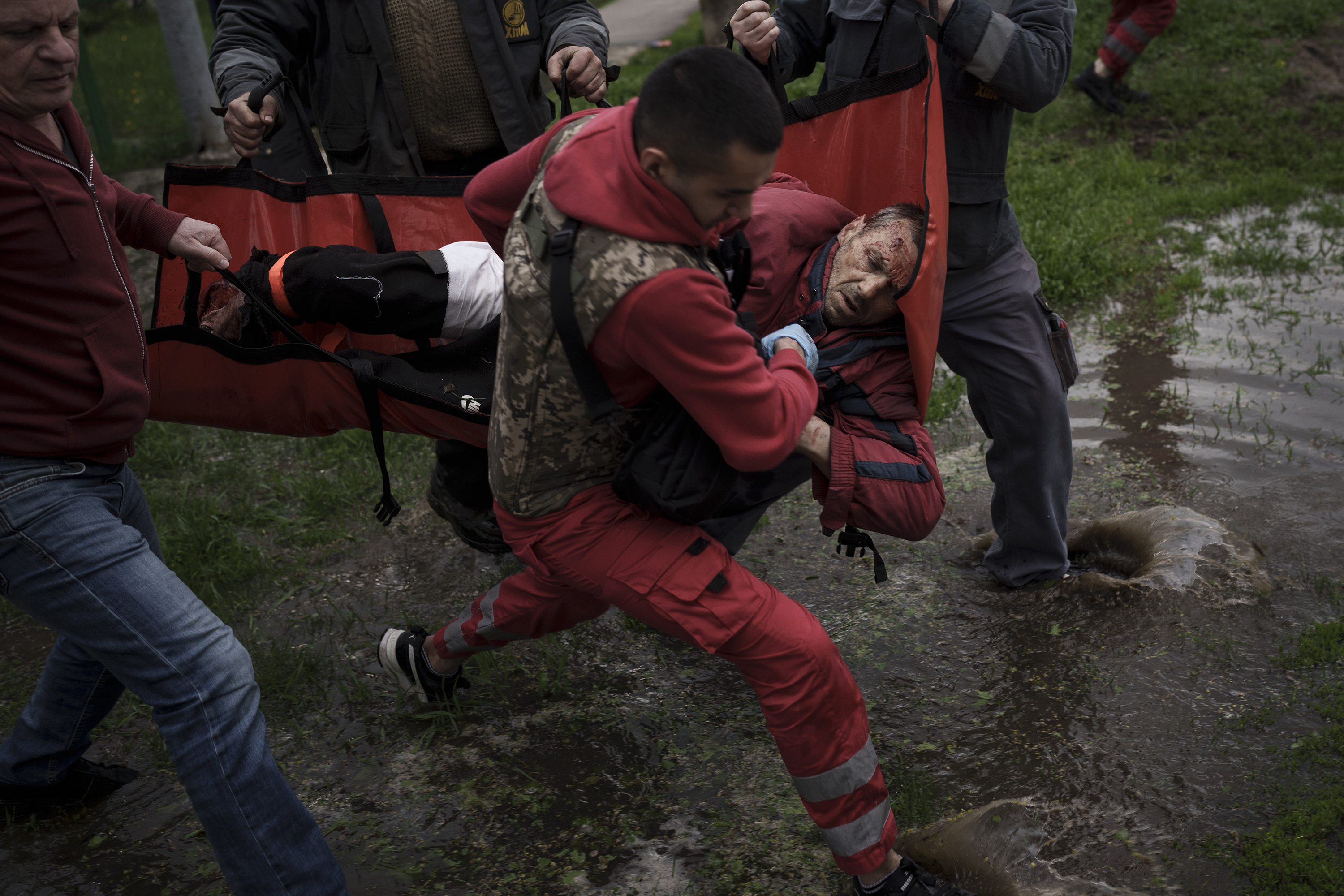 April 27: An emergency worker is helped by locals to carry a man to an ambulance following a Russian bombardment in Kharkiv, Ukraine.