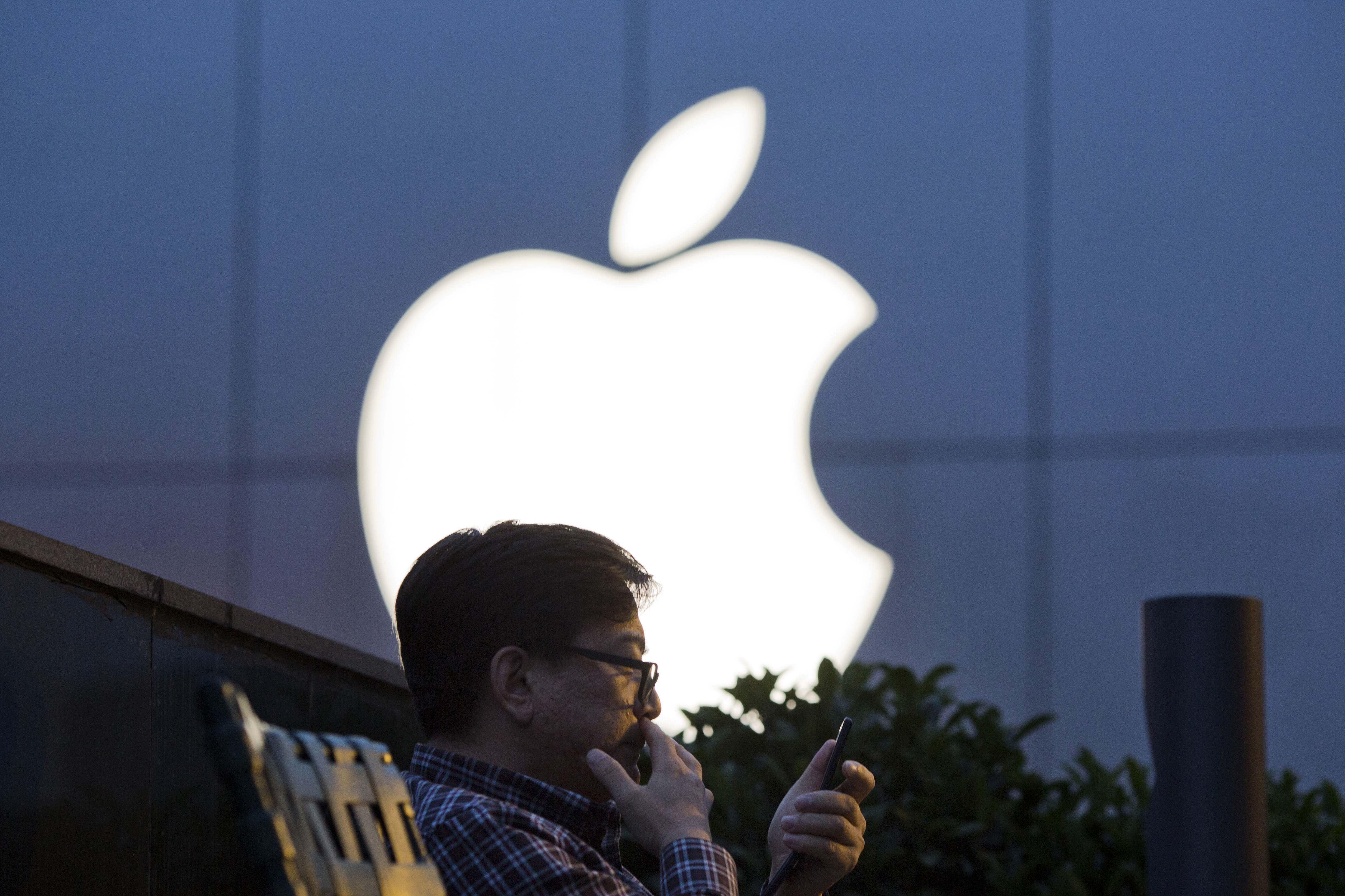 A man uses his mobile phone near an Apple store logo in Beijing. (AP)