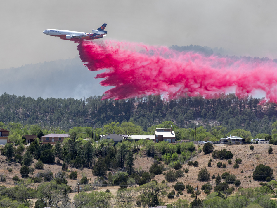 A slurry bomber dumps the fire retardant between the Calf Canyon/Hermit Peak Fire and homes on the westside of Las Vegas, N.M., Tuesday, May 3, 2022.