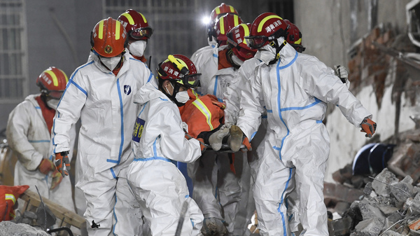 In this photo released by Xinhua News Agency, rescue workers evacuate the 10th survivor pulled alive after being trapped 132 hours from the debris of a self-built residential structure that collapsed in Changsha in central China