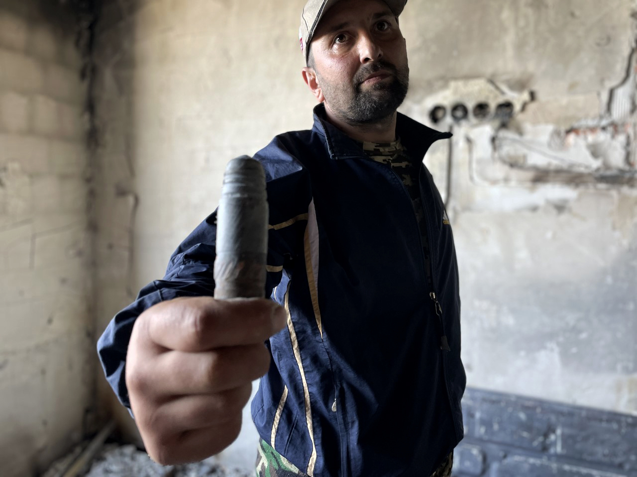 Denis Metrevelyi, 36, holds one of the projectiles that was fired through the window of his apartment in Bucha, a town on the outskirts of Ukraine's capital of Kyiv. Metrevelyi, 36, has returned to the apartment building despite its destroyed roof and lack of running water. (NPR)