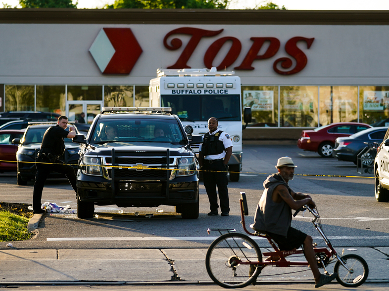 A cyclist pauses passes the scene of a shooting at a supermarket, in Buffalo, N.Y., Sunday, May 15, 2022. (Matt Rourke/AP)