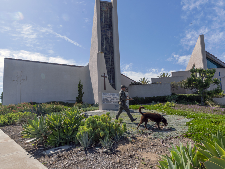 An Orange County Sheriff's Department K-9 unit checks the grounds at Geneva Presbyterian Church in Laguna Woods, Calif. on Sunday after a fatal shooting. (Damian Dovarganes/AP)