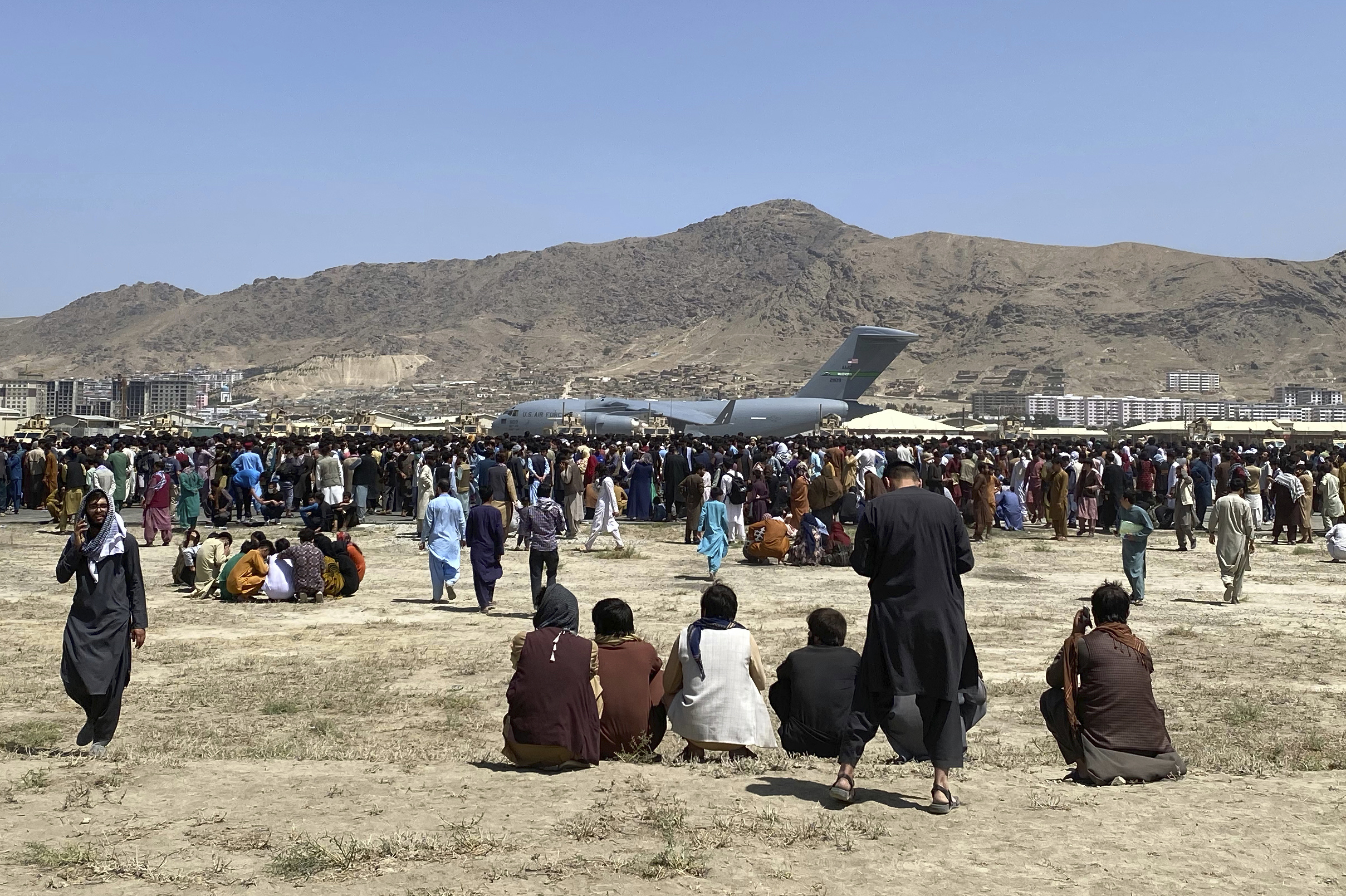 Hundreds of people gather near a U.S. Air Force C-17 transport plane at the perimeter of the international airport in Kabul, Afghanistan, on Aug. 16, 2021.