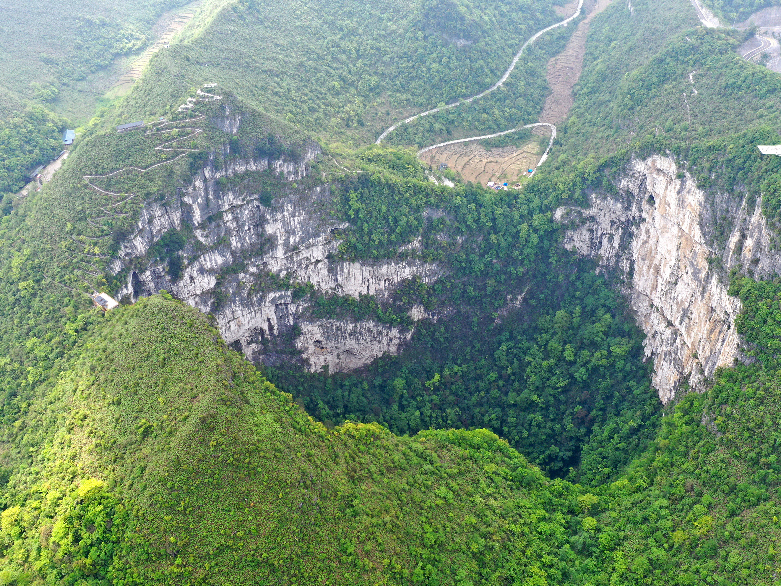 An aerial photo taken in April 2020 shows the scenery of a giant karst sinkhole in China's Guangxi Zhuang Autonomous Region. A similar sinkhole was found earlier this month with an ancient forest at the bottom with trees towering over 100 feet tall. Scientists discover an ancient forest inside a giant sinkhole in China