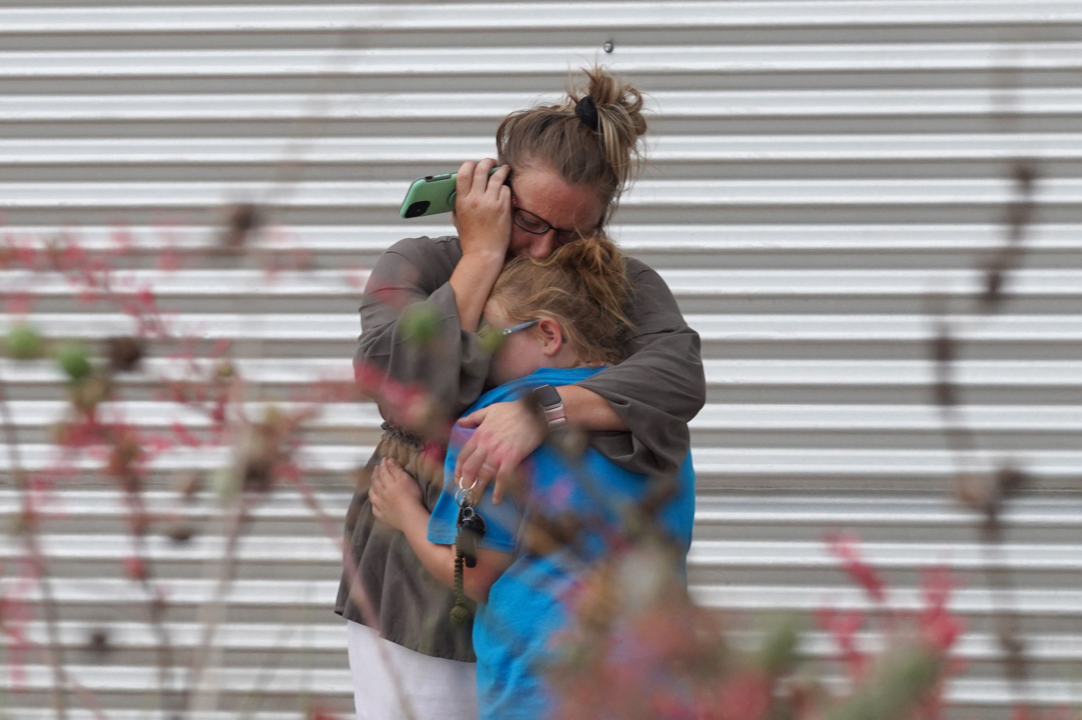 May 24: A woman cries and hugs a young girl while on the phone outside the Willie de Leon Civic Center where grief counseling will be offered in Uvalde, Texas.