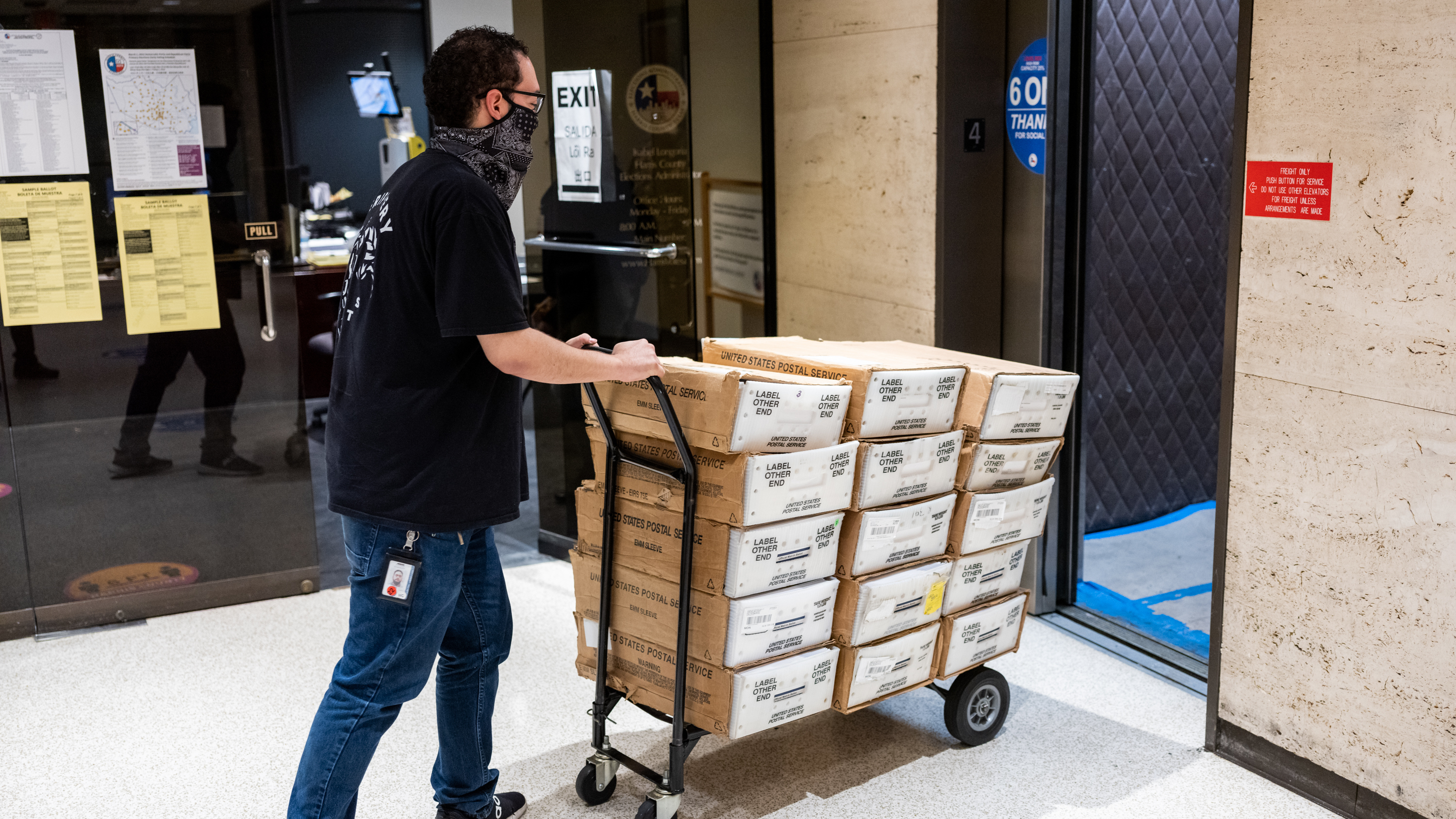 In February, ahead of the Texas statewide primary, Carlos Vanegas at the Harris County Elections Office in Houston pushes a cart with mail-in ballots to be sent to voters. The county ultimately rejected thousands of the mail ballots it received back. (Scott Dalton for NPR)