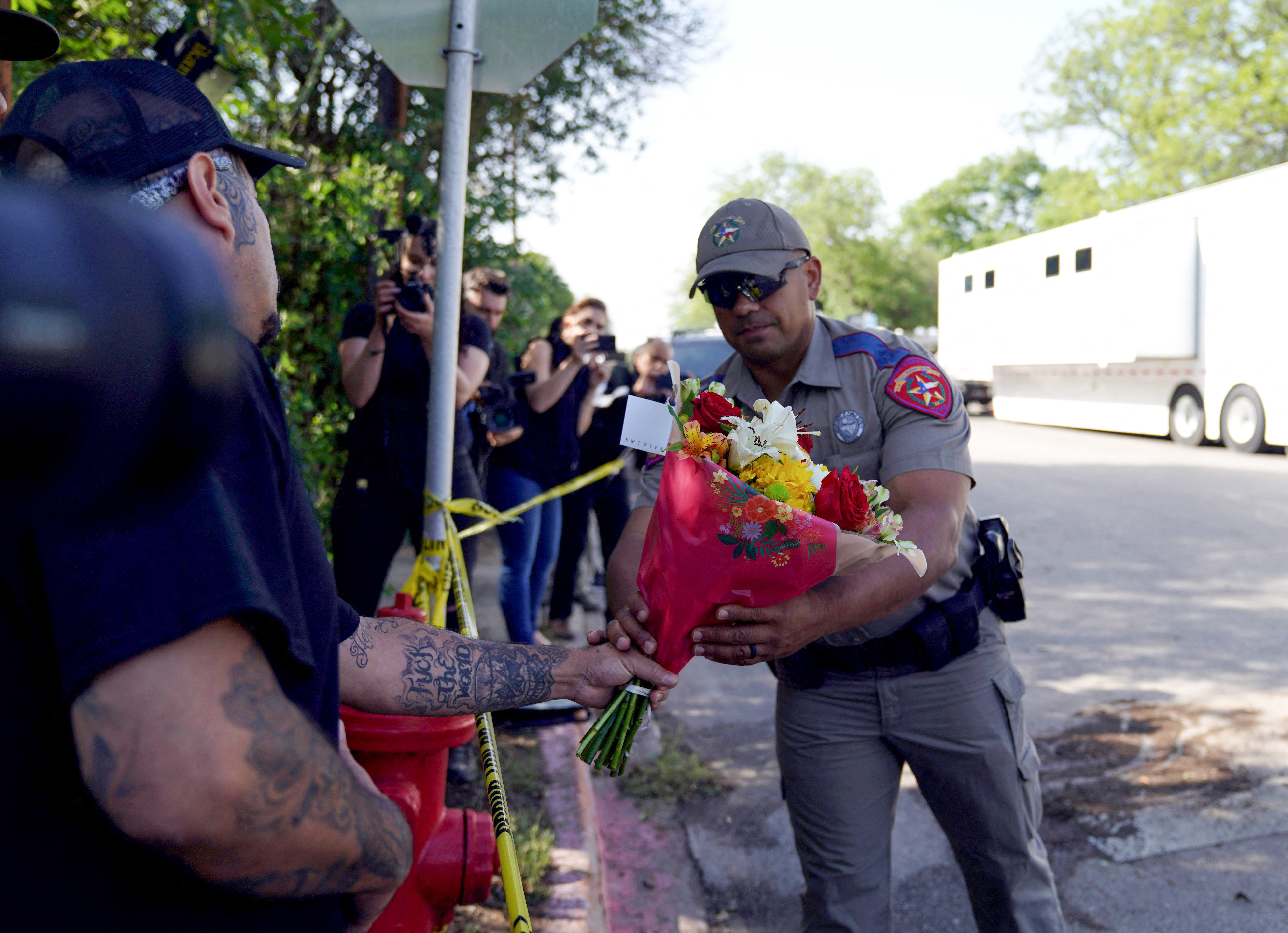May 25: A police officer takes flowers from a resident to be placed at a makeshift memorial outside Robb Elementary School.