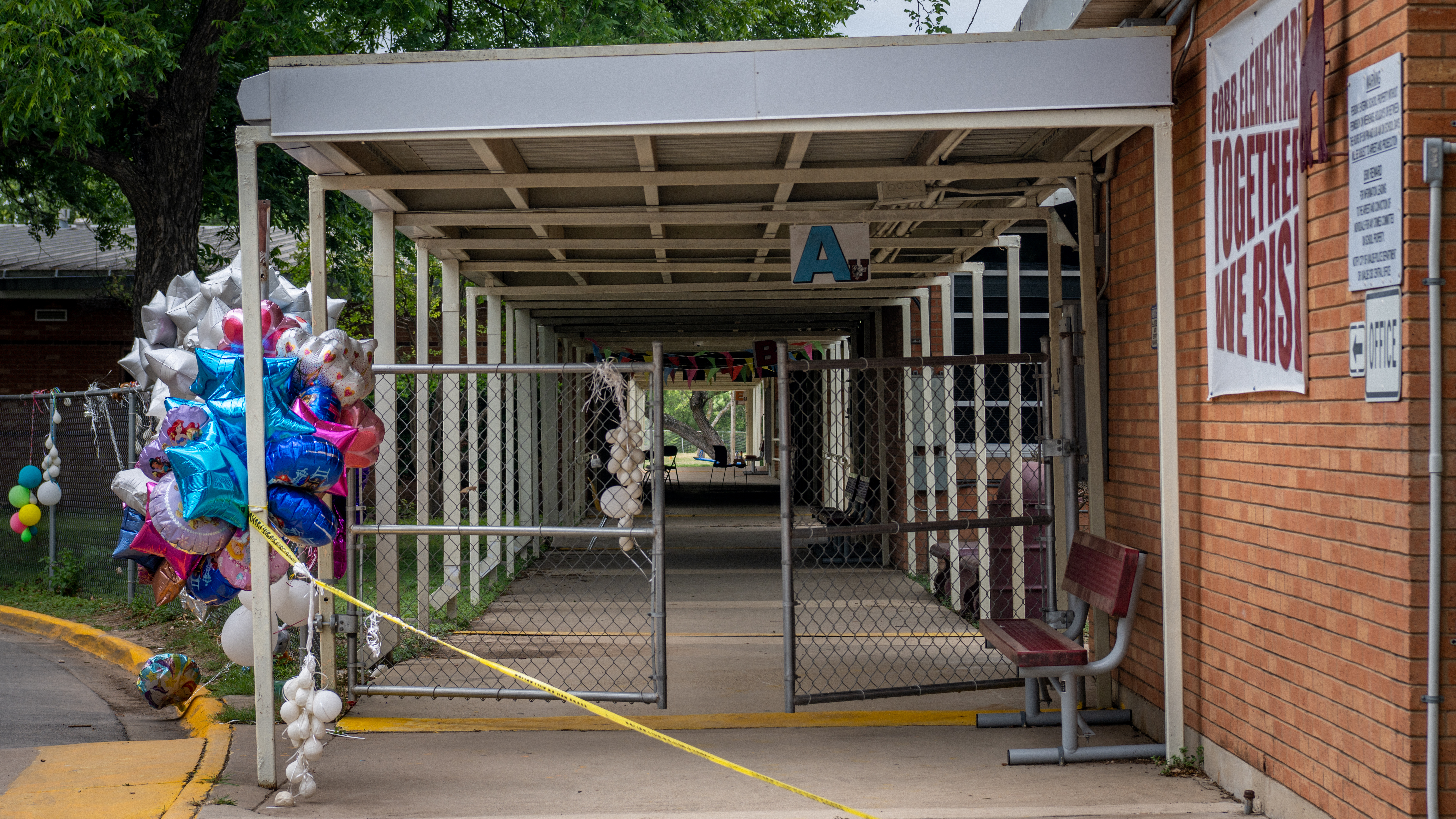 Balloons and caution tape are seen at the entrance to Robb Elementary School in Uvalde, Texas, on Tuesday. Investigators had initially said a teacher left a back door propped open at the school, but that account has now shifted. (Getty Images)