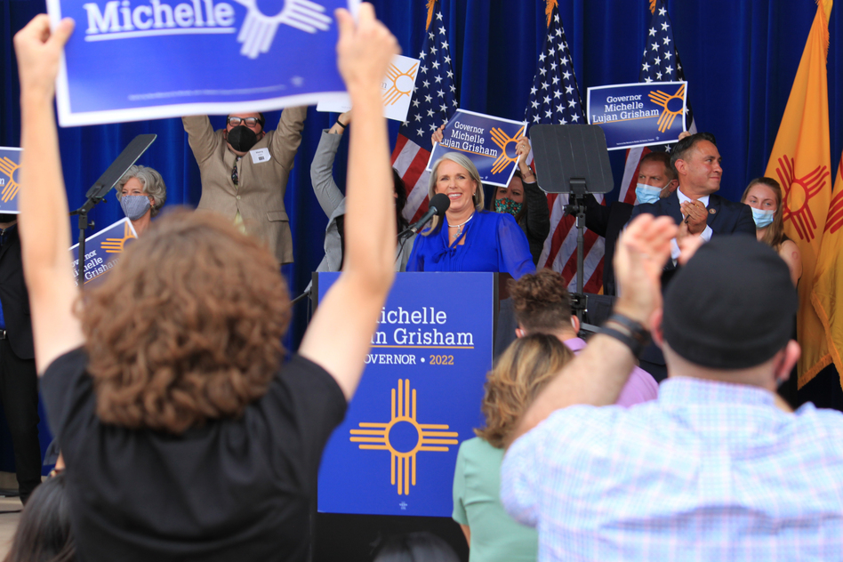 New Mexico's Democratic governor, Michelle Lujan Grisham (center), smiles as supporters cheer during a campaign rally in Albuquerque, N.M., on June 3, 2021. The rally was cut short as protesters chanted loudly beyond the walls of the outdoor venue.