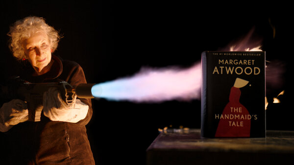 Margaret Atwood aims a flamethrower at a copy of her book, The Handmaid's Tale.