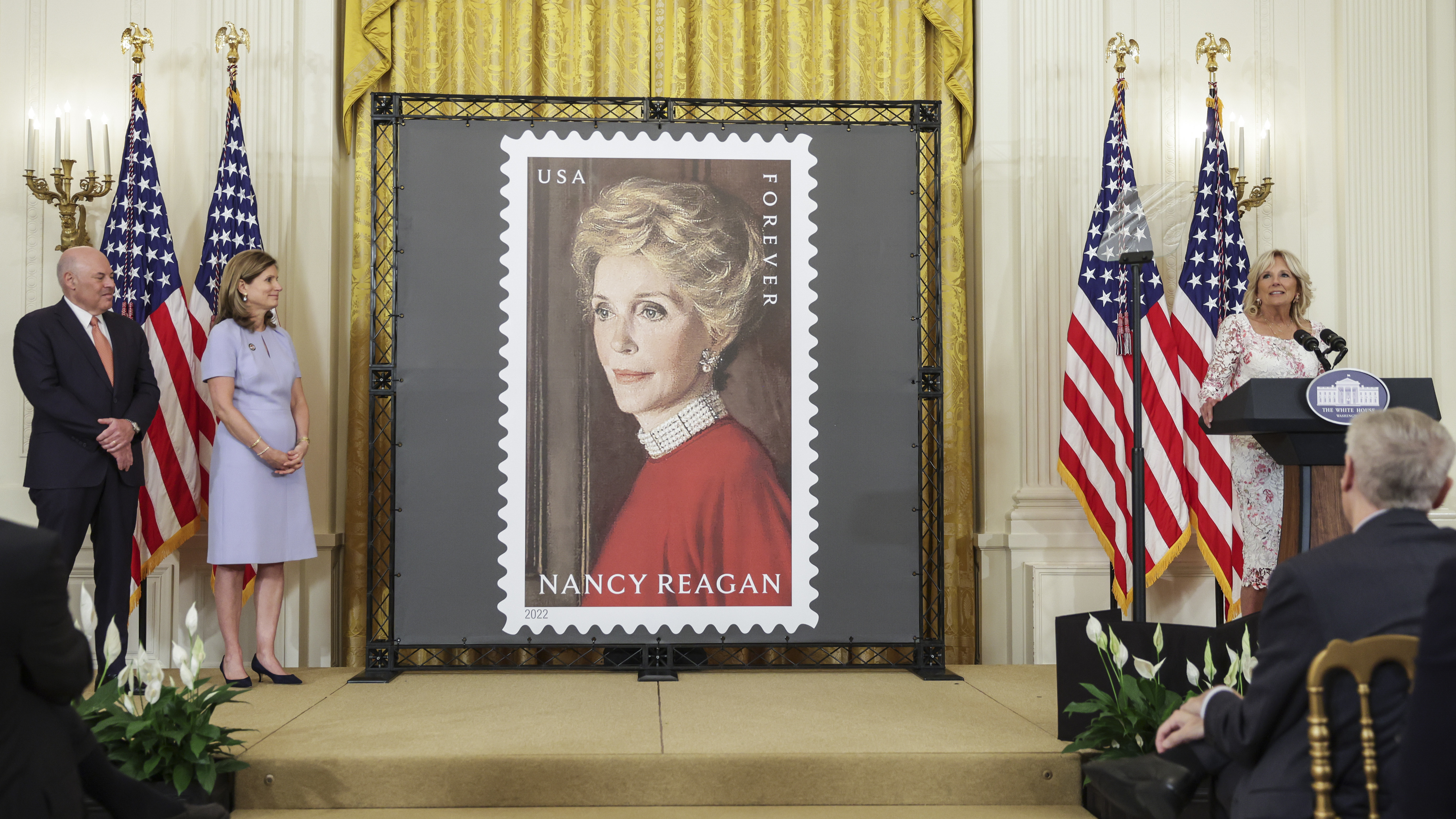 First lady Jill Biden (right) speaks onstage with Postmaster General Louis DeJoy and Anne Peterson, former first lady Nancy Reagan's niece, at the unveiling of the Nancy Reagan stamp at the White House on Monday. (Getty Images)