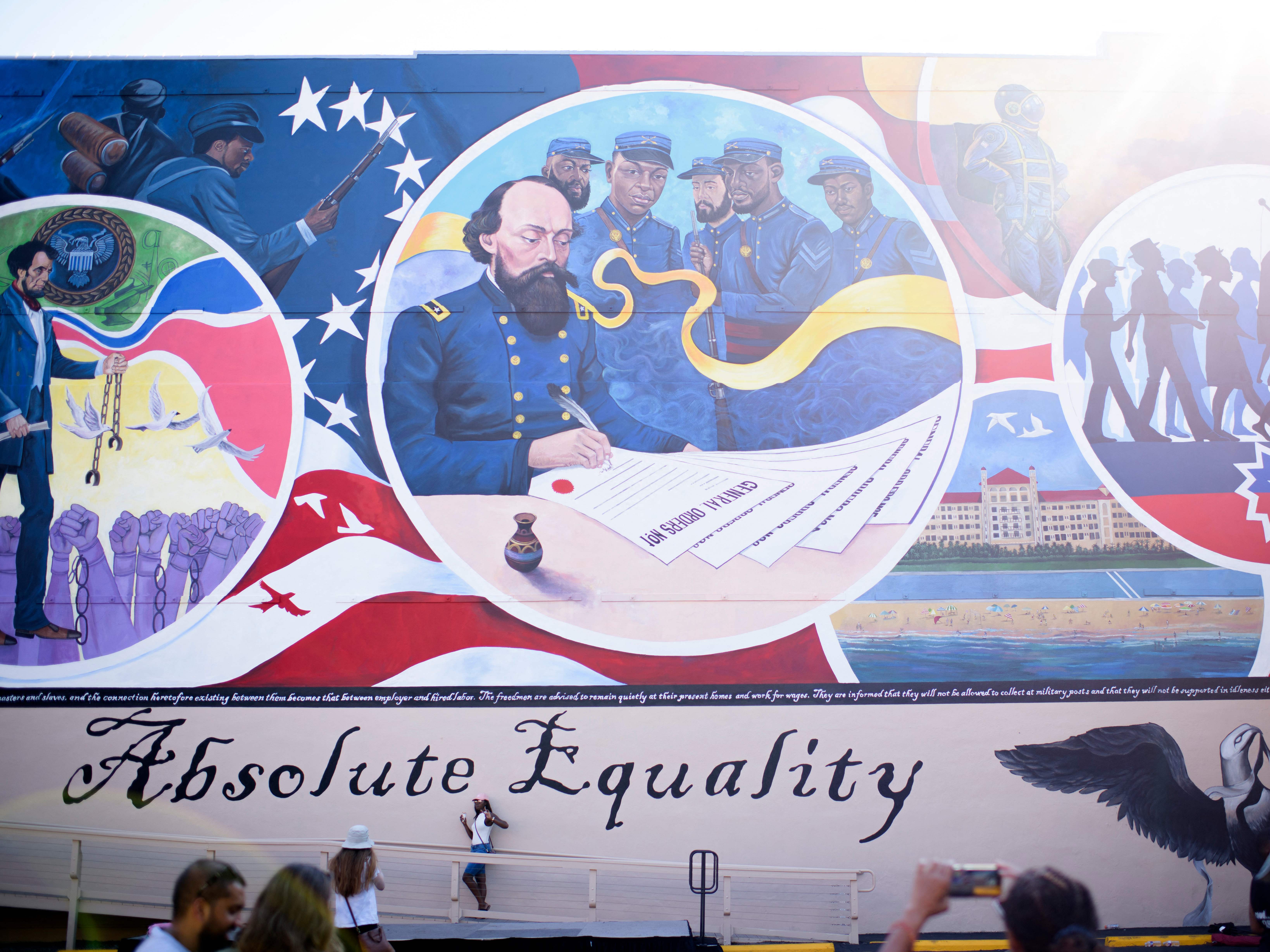 People take pictures next to a mural during a Juneteenth celebration in Galveston, Texas, on June 19, 2021. Last year, the U.S. designated Juneteenth a federal holiday with President Joe Biden urging Americans &quot;to learn from our history.&quot; (AFP via Getty Images)