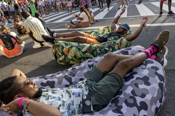 Friends Ibrahim Hydara, from Rockville, Md. (center with hat), and Rasheed Billy, from Baltimore, Md., lounge in their inflatable couches as they take in the scene at the music festival on Friday, June 17.