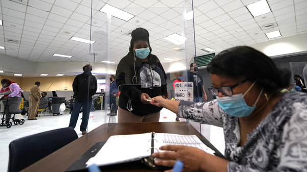 A voter presents identification at a polling site for the 2020 elections in New Orleans. The U.S. Supreme Court has temporarily blocked a lower court