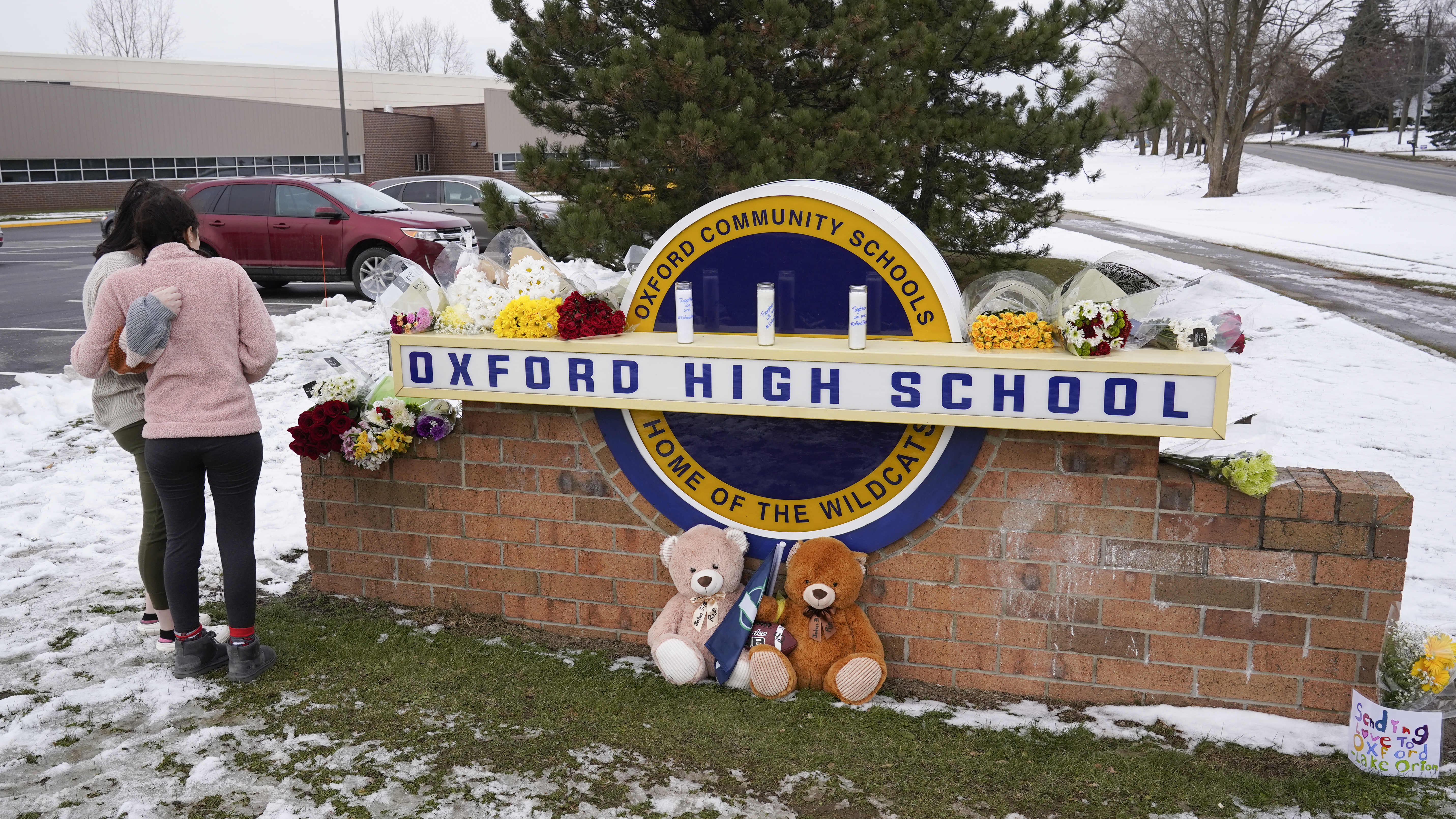 Students stand outside Oxford High School, near memorial items that were placed after the November 2021 shooting that took place at the Michigan school.