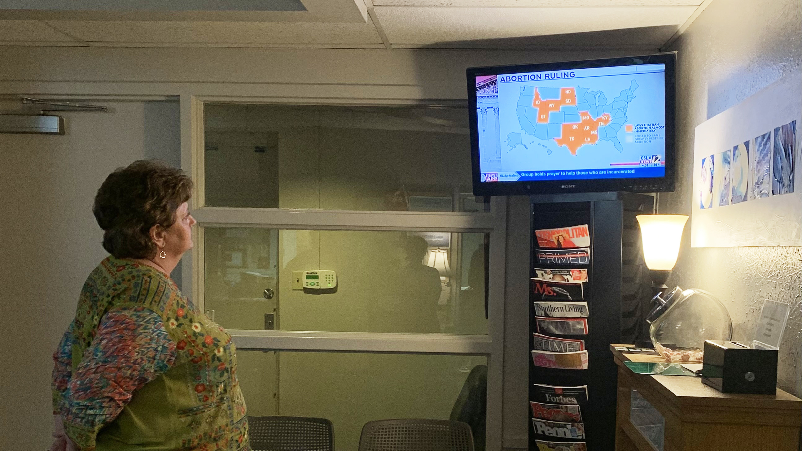 Kathaleen Pittman, administrator at Hope Medical Group in Shreveport, watches local TV news discussing a temporary restraining order the clinic won on Monday against Louisiana's abortion bans. (NPR)