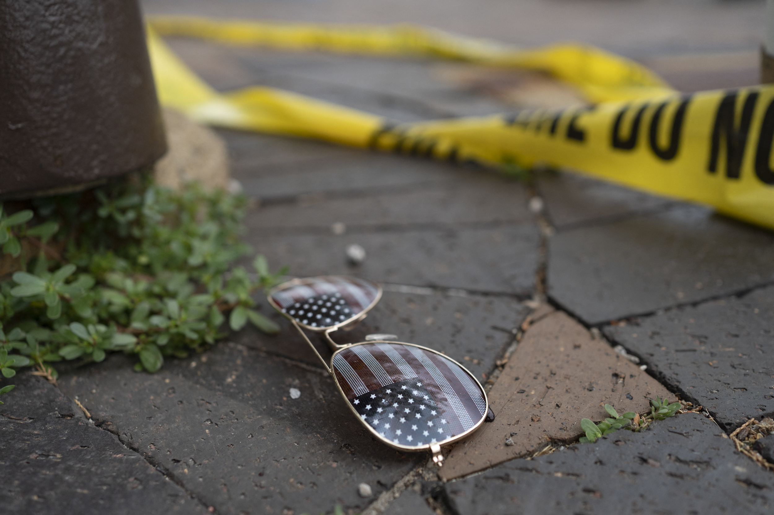 Police crime tape is seen near an American flag-themed sunglasses at the scene of the Fourth of July parade shooting in Highland Park, Ill. (AFP via Getty Images)