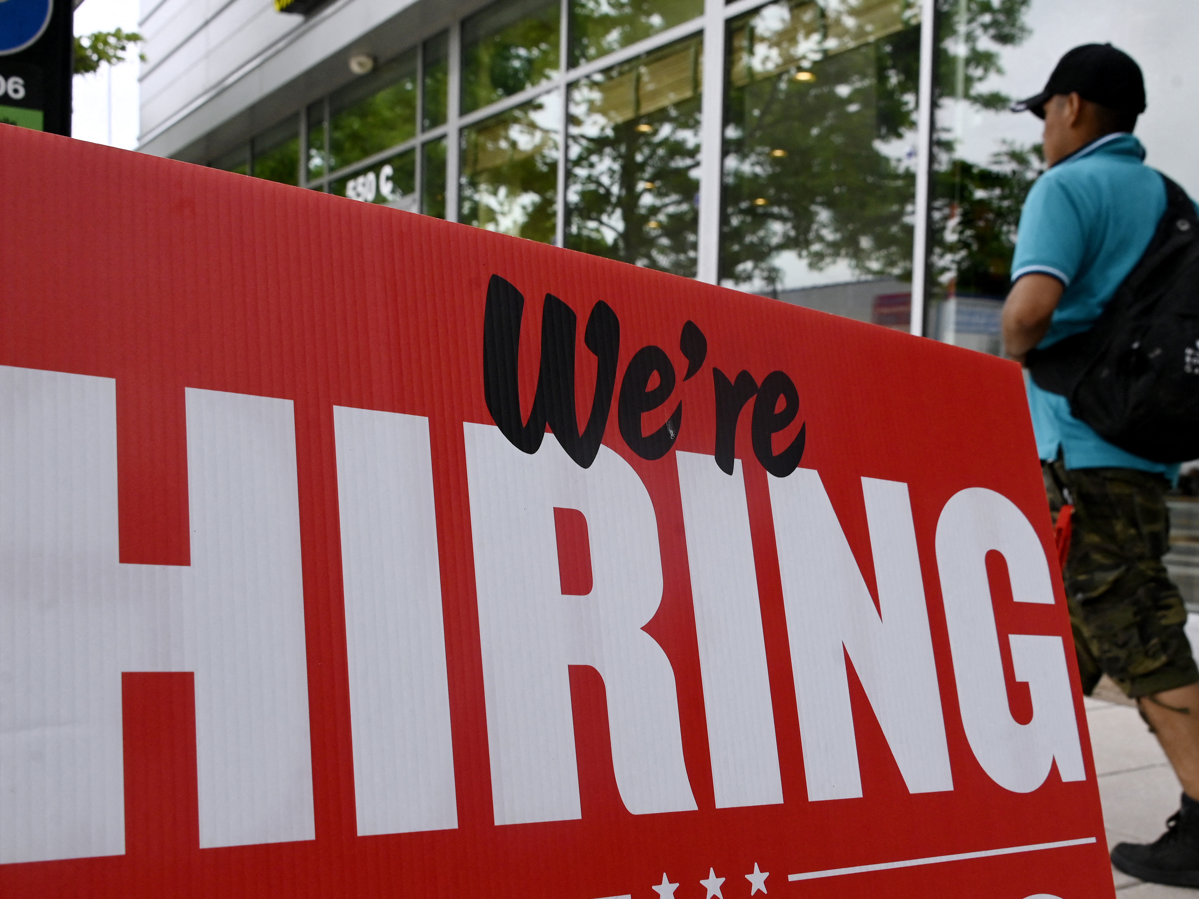 Fewer jobs were added in June, but the labor market is still tight. A man walks past a "now hiring" sign posted outside of a restaurant in Arlington, Va., last month. (AFP via Getty Images)