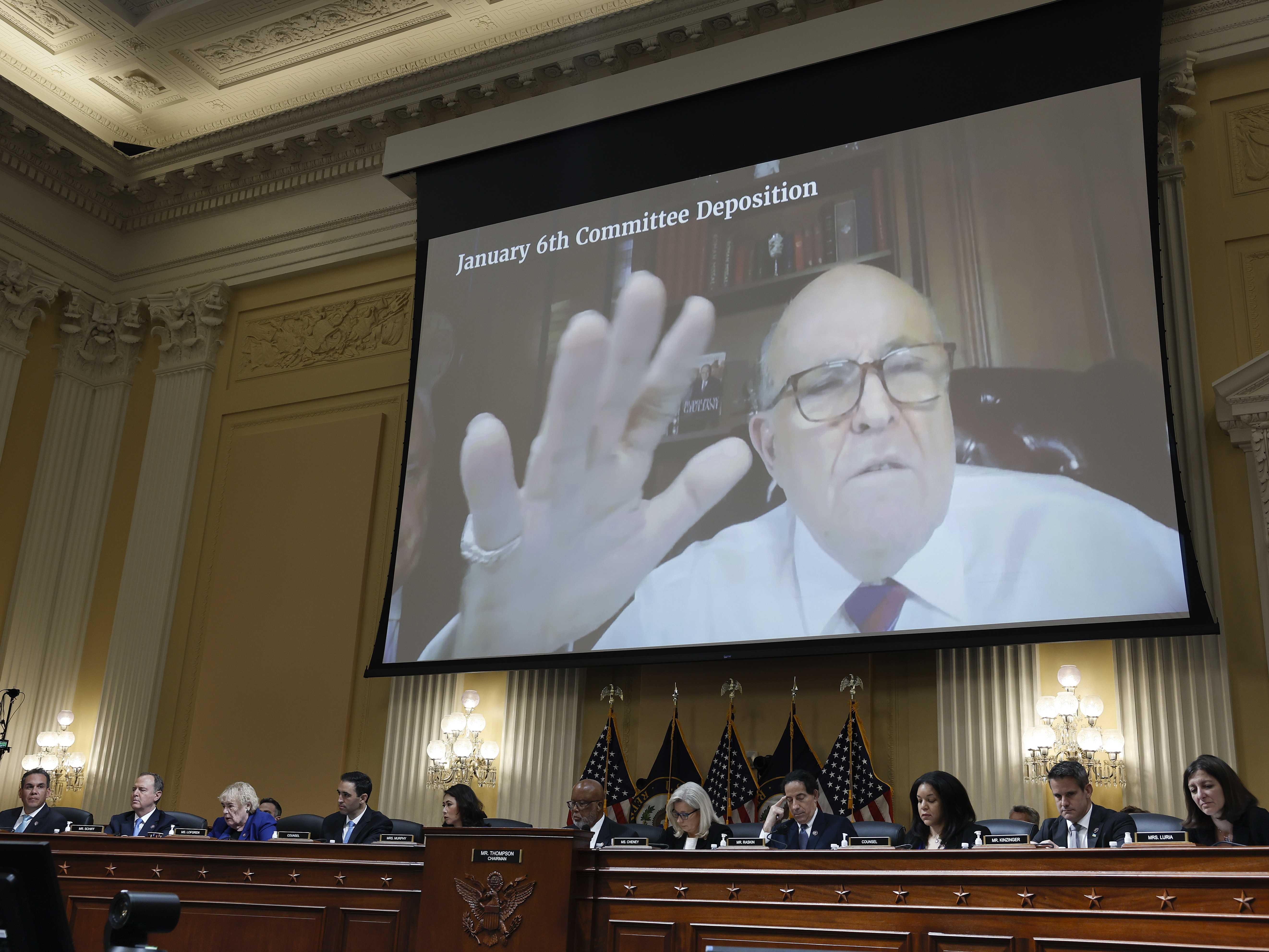 Rudy Giuliani's videotaped testimony appears on a video screen above members of the Select Committee to Investigate the January 6th Attack on the U.S. Capitol during its seventh hearing on July 12, 2022. (Getty Images)