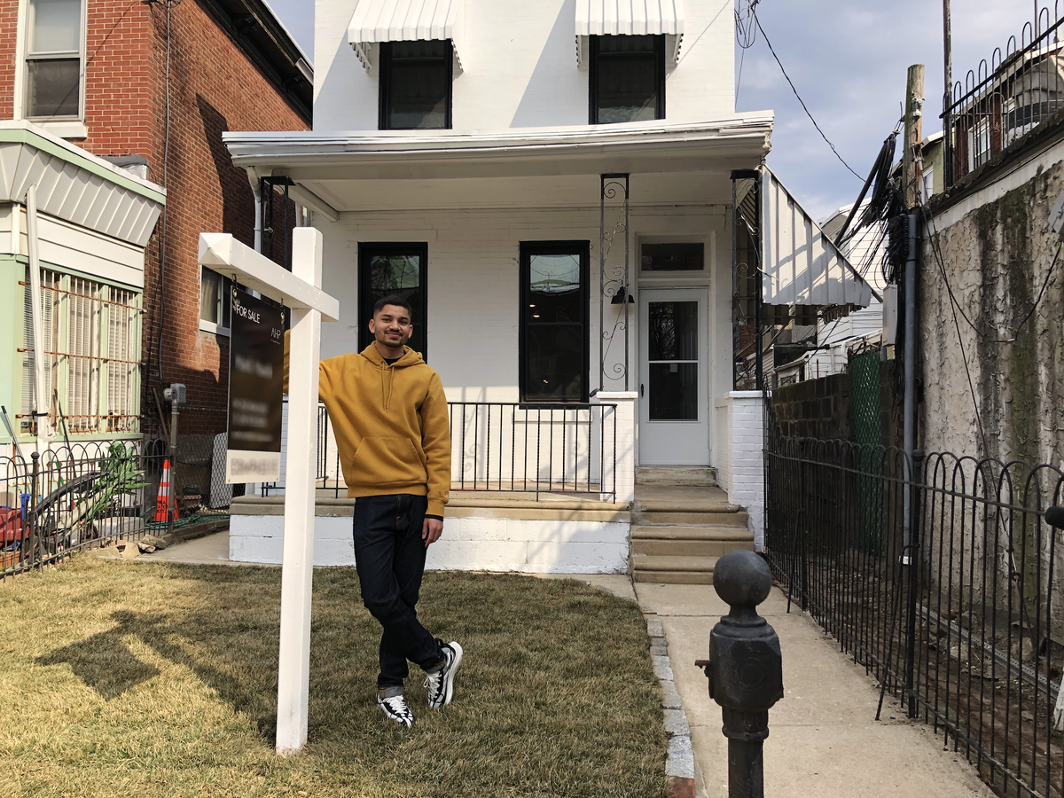 Mark Masih stands in front of a house he is selling with what he dubs "the first crypto fixture ever being sold in the world."