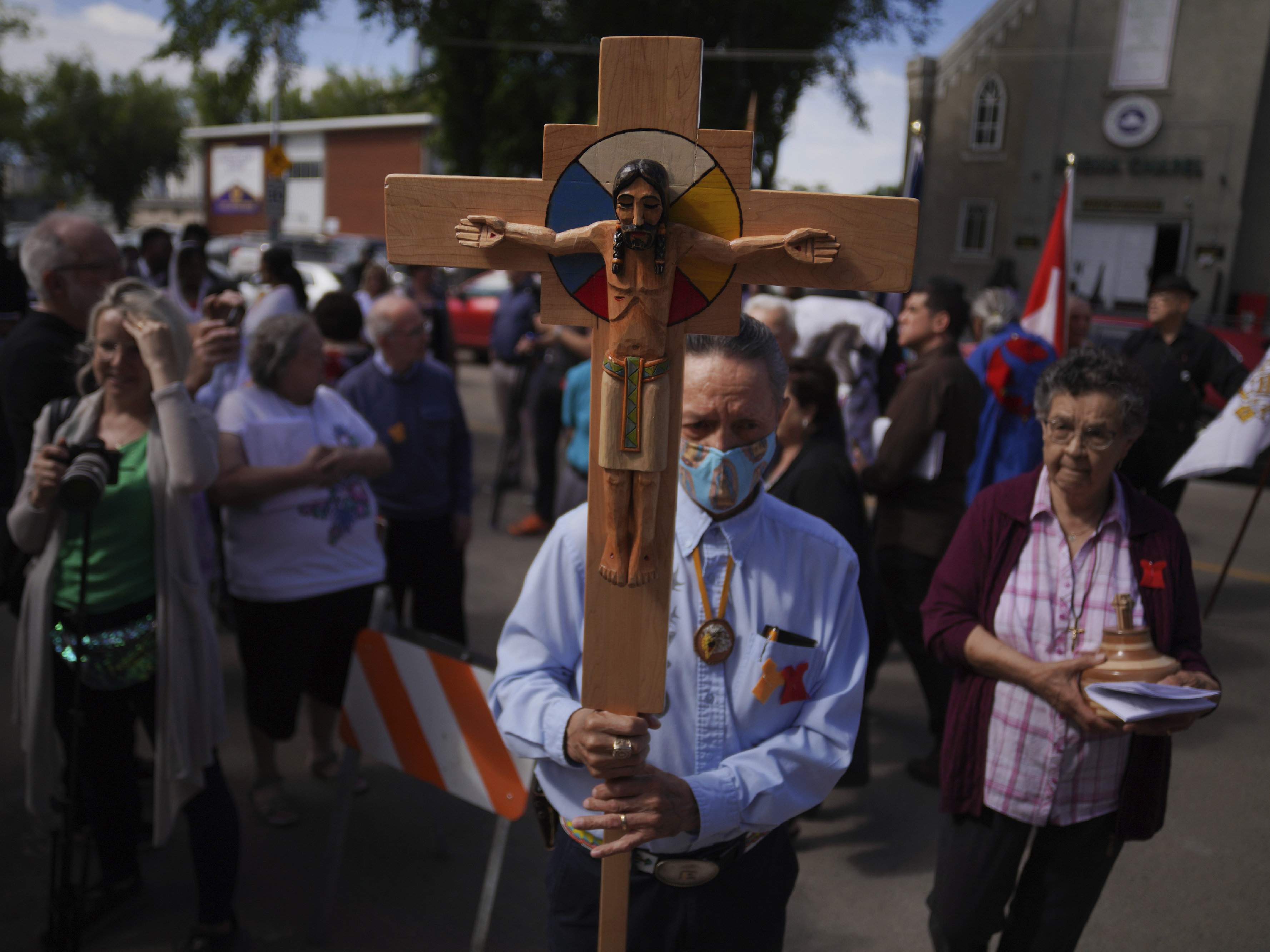 Elmer Waniandy raises the crucifix as he leads his fellow parishioner into the rededicated and newly renovated Sacred Heart Church of the First Peoples sanctuary, last week, in Edmonton, Alberta.