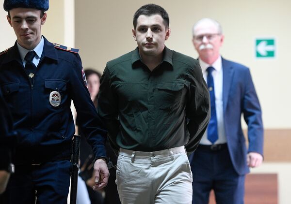 Police officers escort Marine veteran Trevor Reed into a courtroom before a hearing in Moscow on March 11, 2020. In April, Reed was part of a prisoner swap with Russia following a public advocacy campaign by his parents.