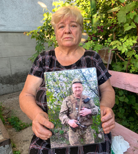 Vira Bilay holds a photo of her late son Andriy Bilay, who worked for the Ukrainian railroad before enlisting to fight. 'People, please don't fight, it is heartbreaking. It's very painful. Don't kill each other!' she cries.