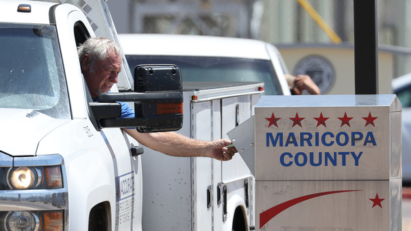 A voter places a ballot in a drop box outside of the Maricopa County Elections Department on August 02, 2022 in Phoenix, Arizona. Arizonans are voting in the state