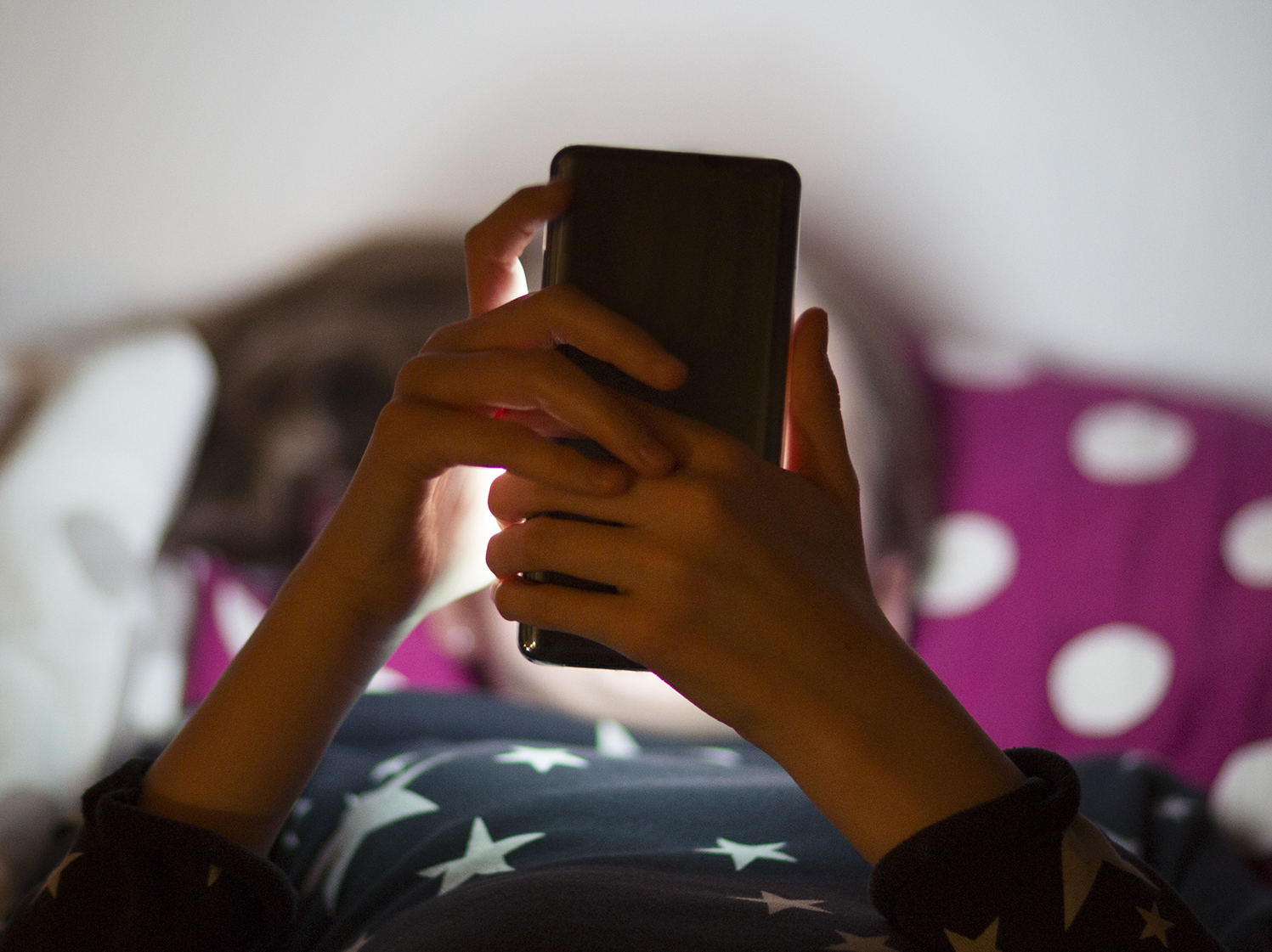 Snapchat is rolling out new parental controls that allow parents to see their teenager's contacts and confidentially report to the social media company any accounts that concern them. A child lies in bed illuminated by the glow of a cell phone. (Getty Images)