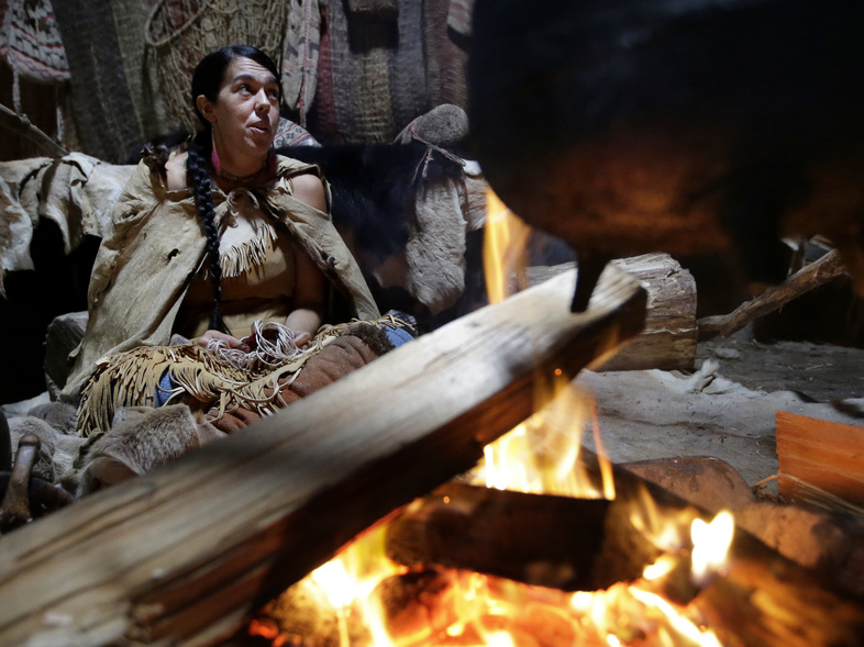 Mashpee Wampanoag Kerri Helme uses plant fiber to weave a basket while sitting next to a fire on November 15, 2018, at the Wampanoag Homesite at the Plimoth Patuxet Museums, in Plymouth, Mass. (Steven Senne/AP)