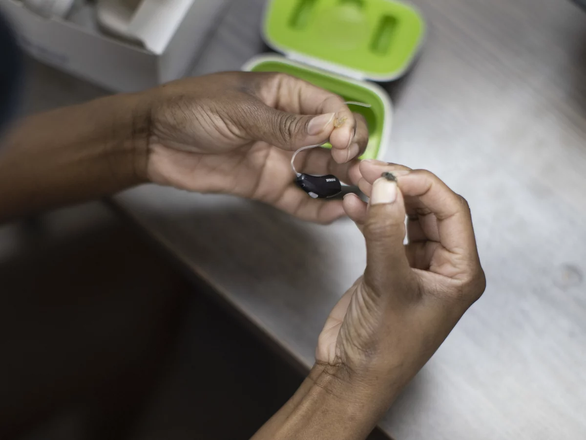 black hearing aids being held by 2 hands