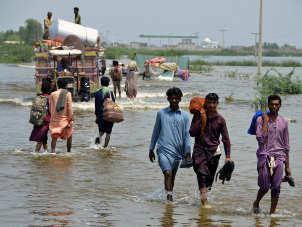 People wade through a flooded area in Pakistan, that has been dealing with what people are calling "monster monsoons".