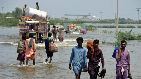 People wade through a flooded area in Pakistan, that has been dealing with what people are calling "monster monsoons".
