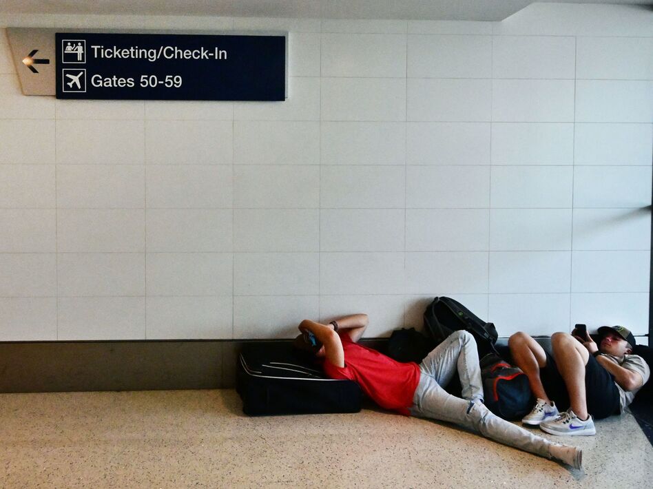 Travelers rest on the ground while waiting for their flights at Los Angeles International Airport on July 1. On Thursday, the U.S. Transportation Department is rolling out a new website that will allow passengers to see what they're legally entitled to when an airline cancels or significantly delays their flight.